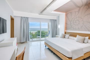 a bedroom with a large window and a view of the ocean