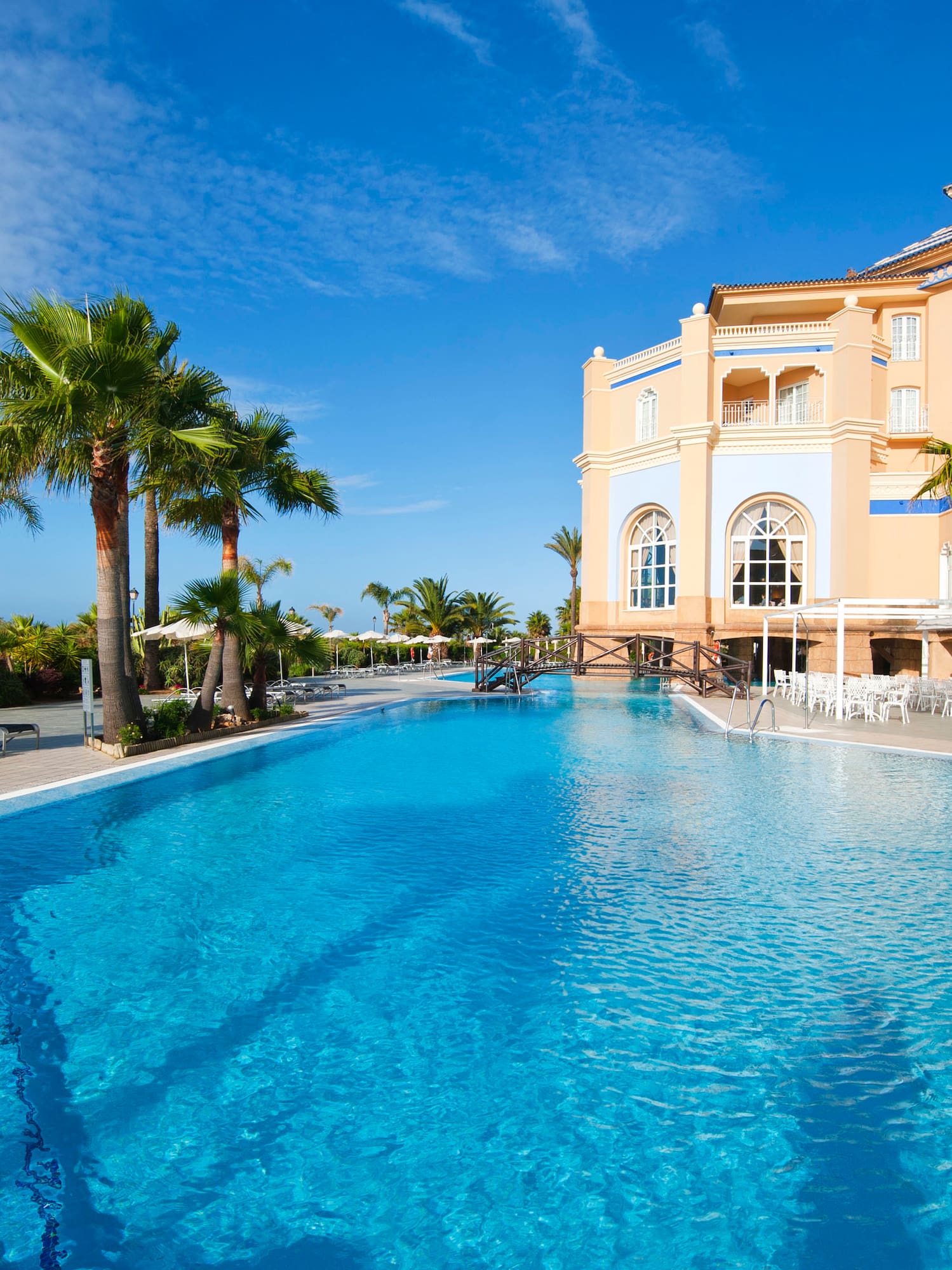 a pool with palm trees and a building