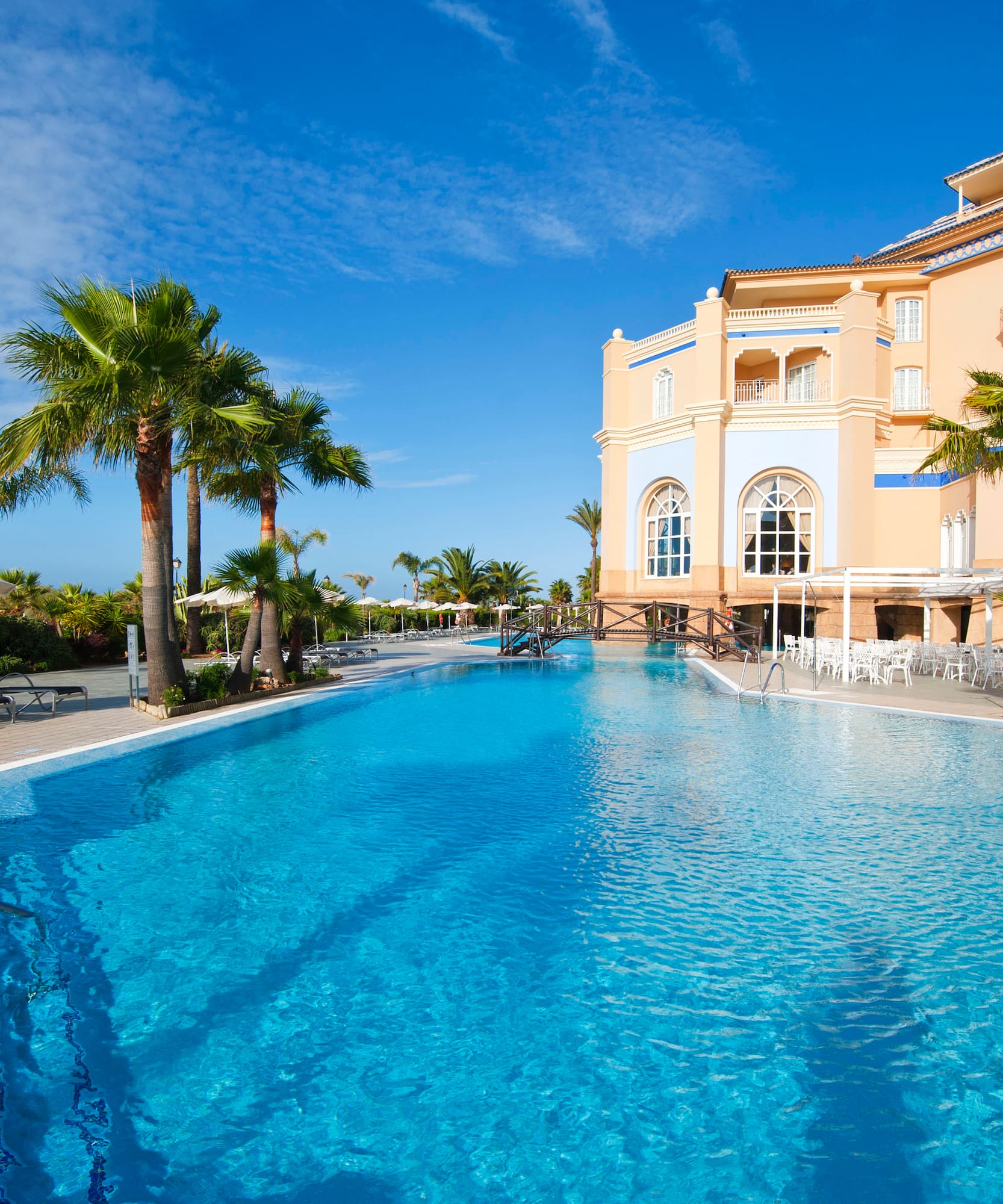 a pool with palm trees and a building