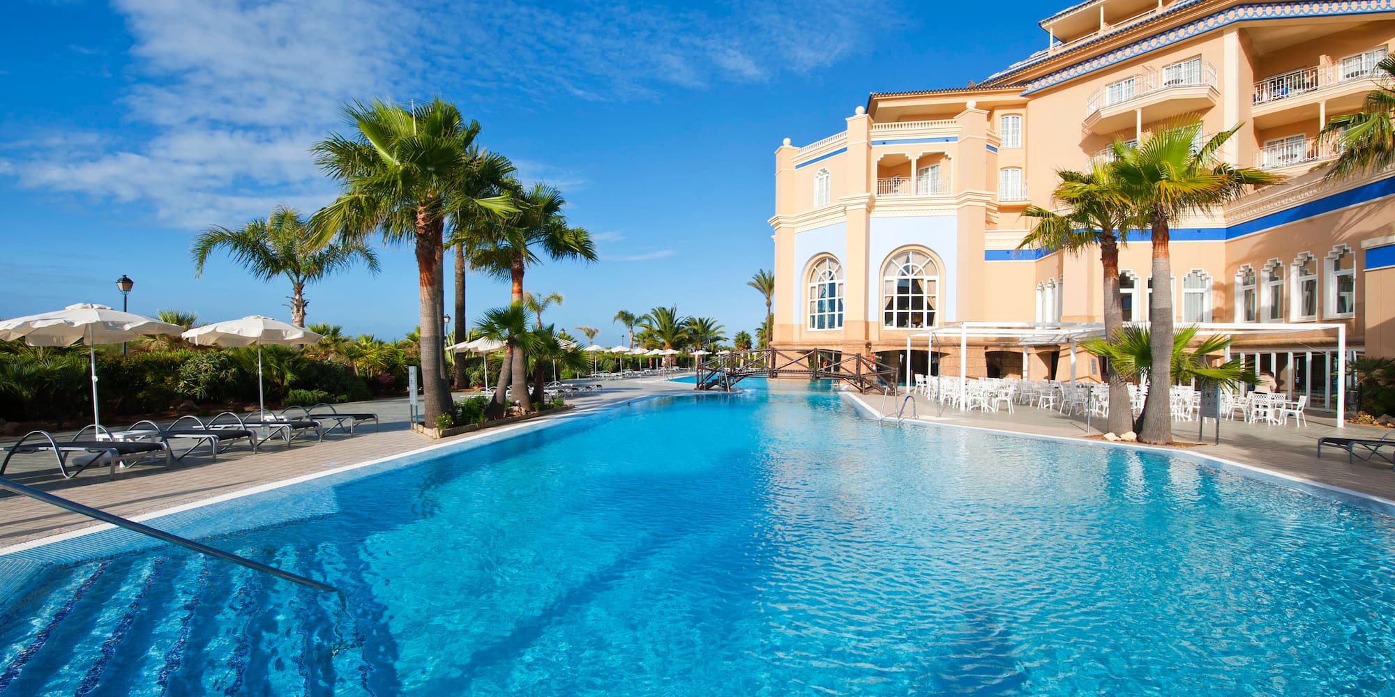 a pool with palm trees and a building