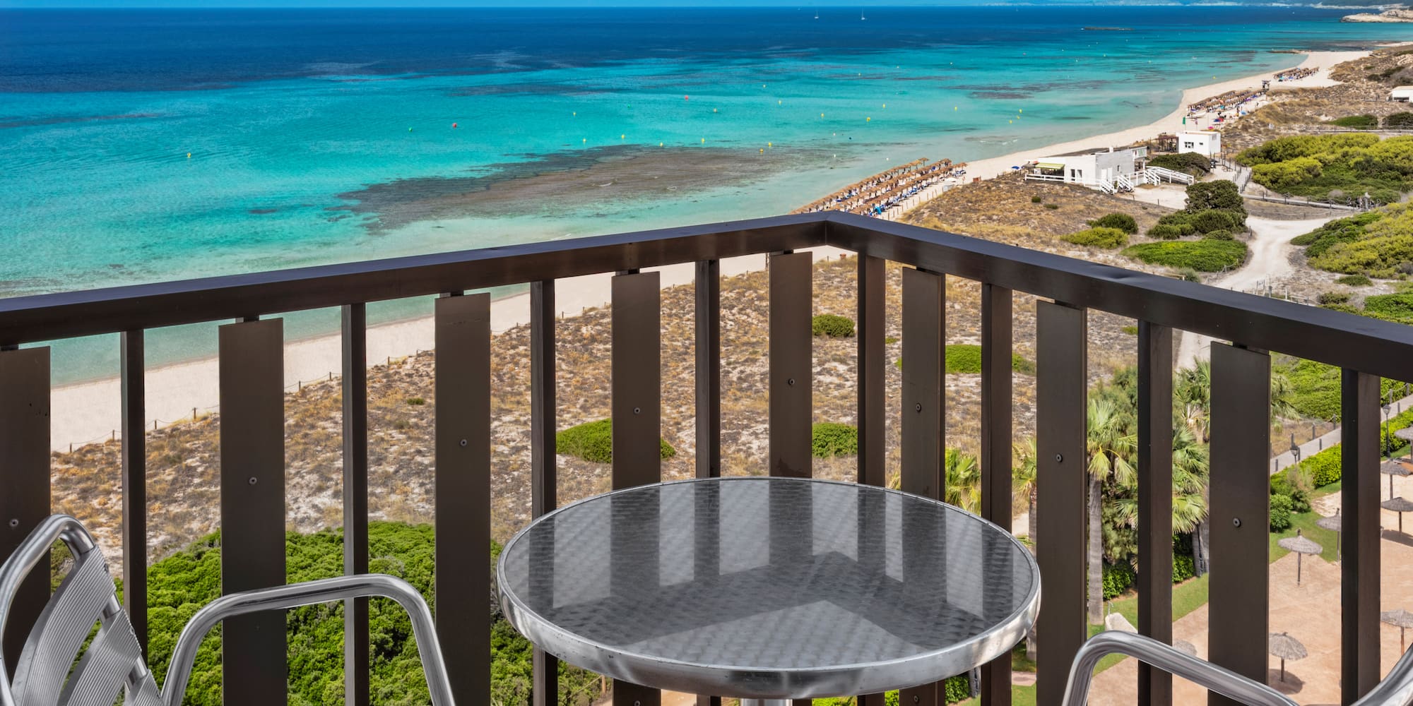 a table and chairs on a balcony overlooking a beach