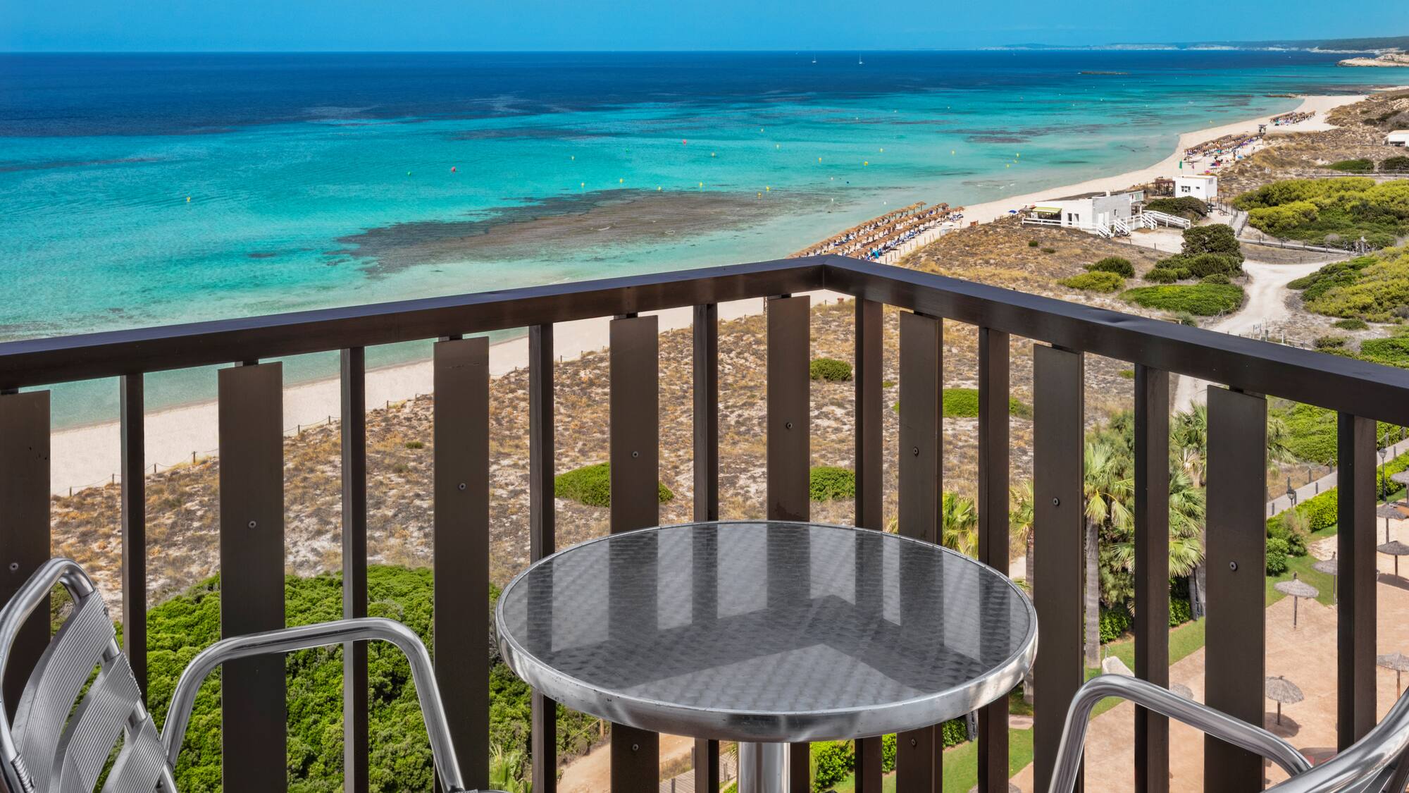 a table and chairs on a balcony overlooking a beach