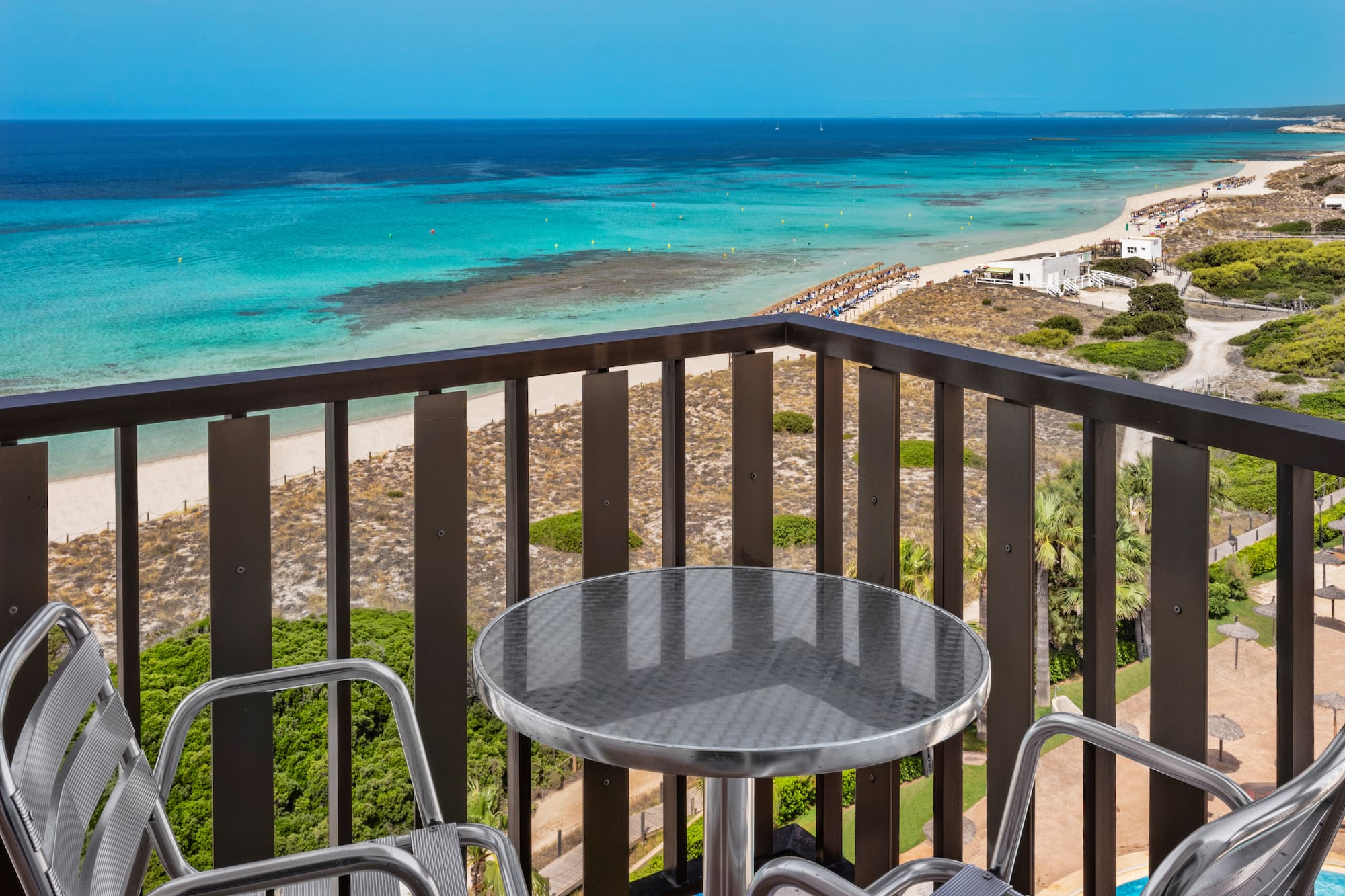 a table and chairs on a balcony overlooking a beach