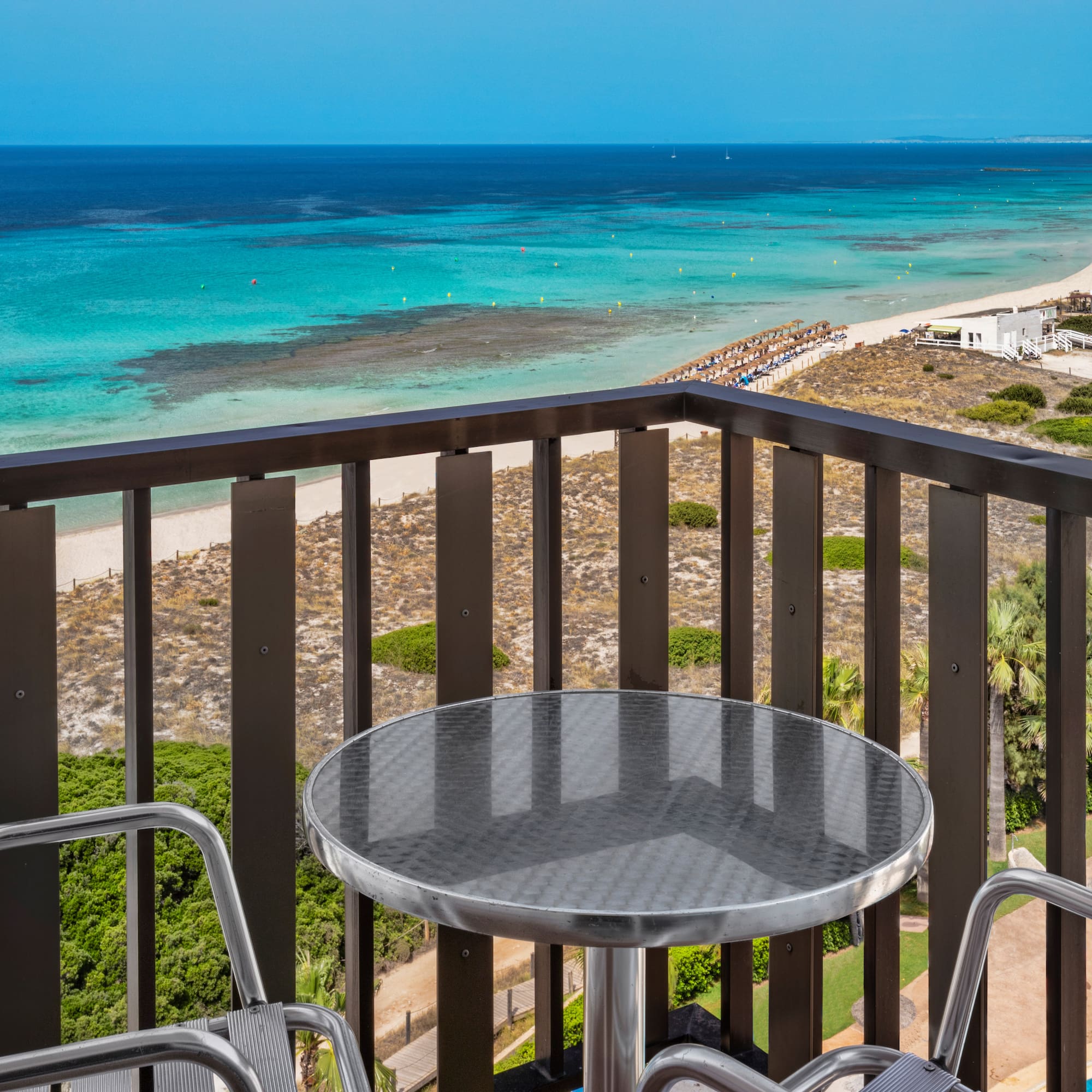 a table and chairs on a balcony overlooking a beach