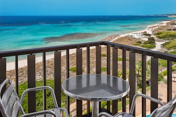a table and chairs on a balcony overlooking a beach