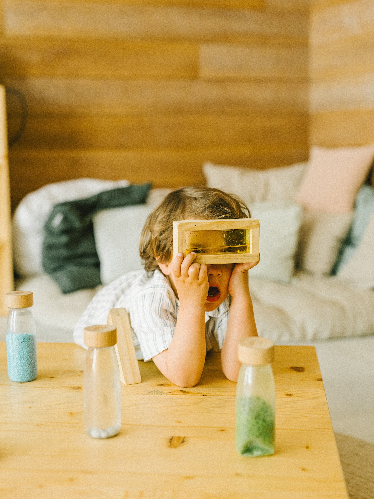 Niño explorando con bloque sensorial de madera líquido en mesa de madera.
