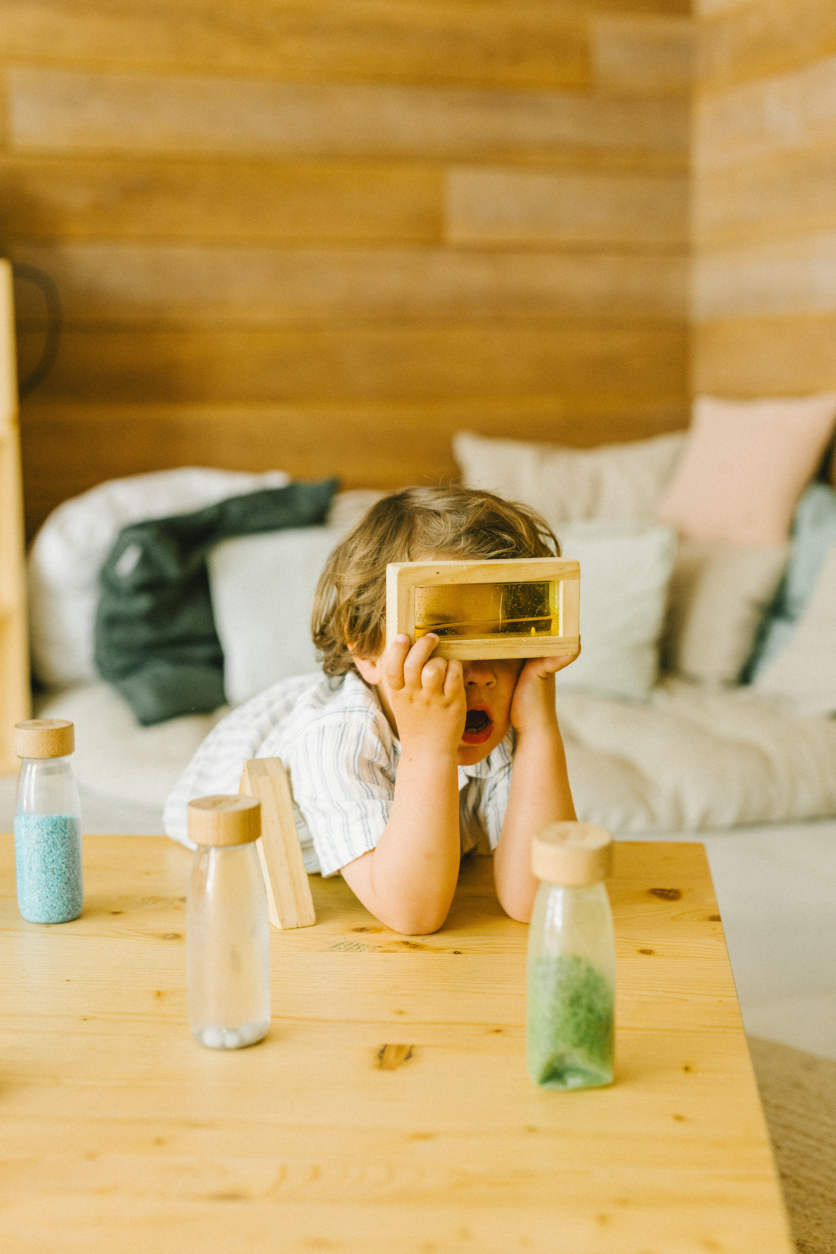 Niño explorando con bloque sensorial de madera líquido en mesa de madera.