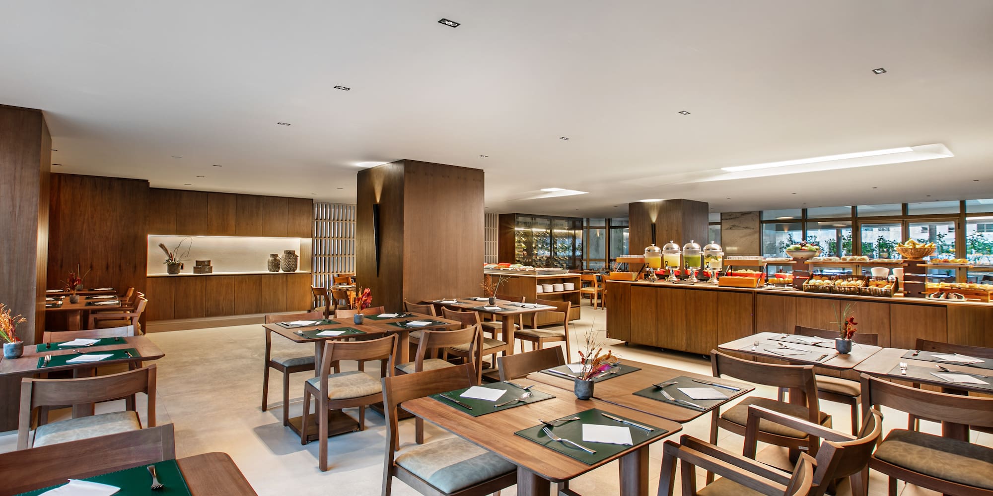 Modern restaurant dining area with wooden tables and a breakfast buffet.