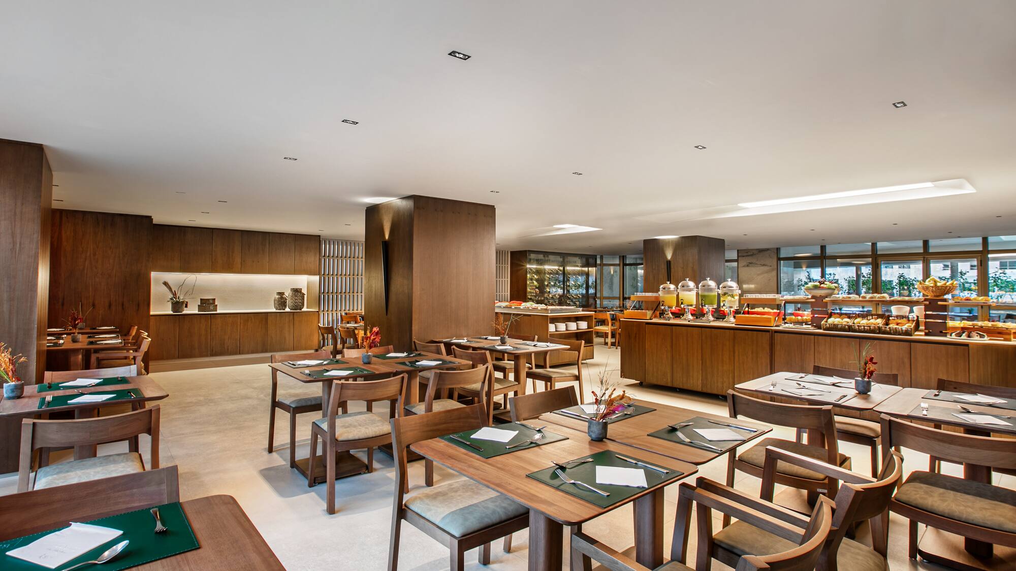 Modern restaurant dining area with wooden tables and a breakfast buffet.