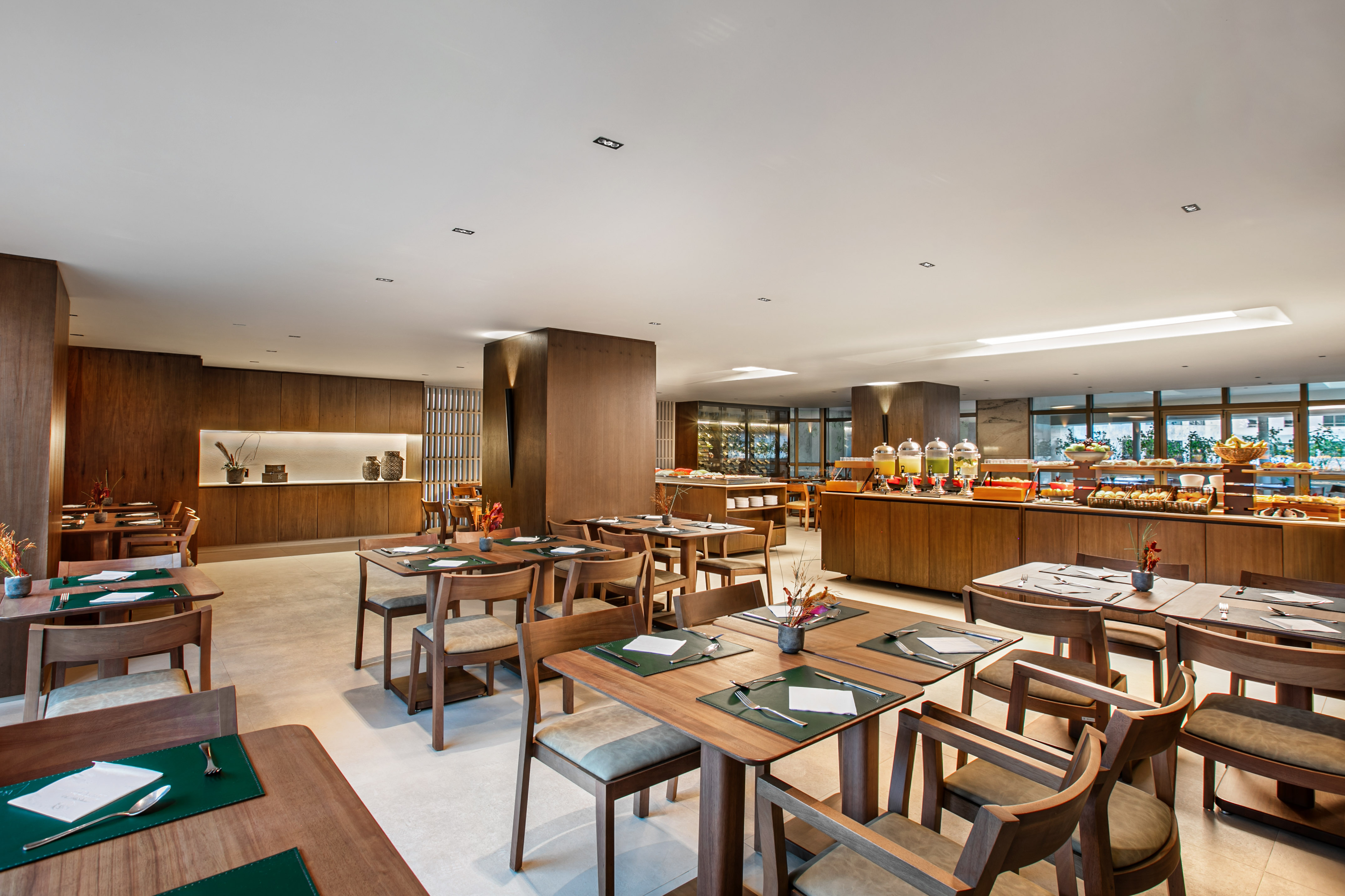 Modern restaurant dining area with wooden tables and a breakfast buffet.