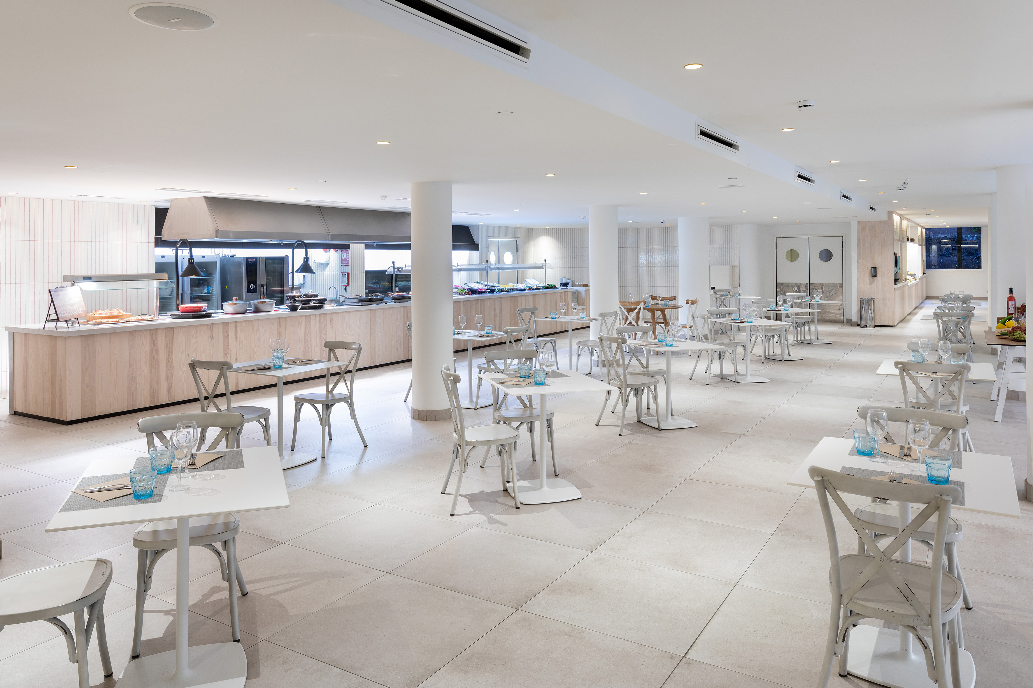 Modern buffet restaurant with bright white seating and light wood food counters.