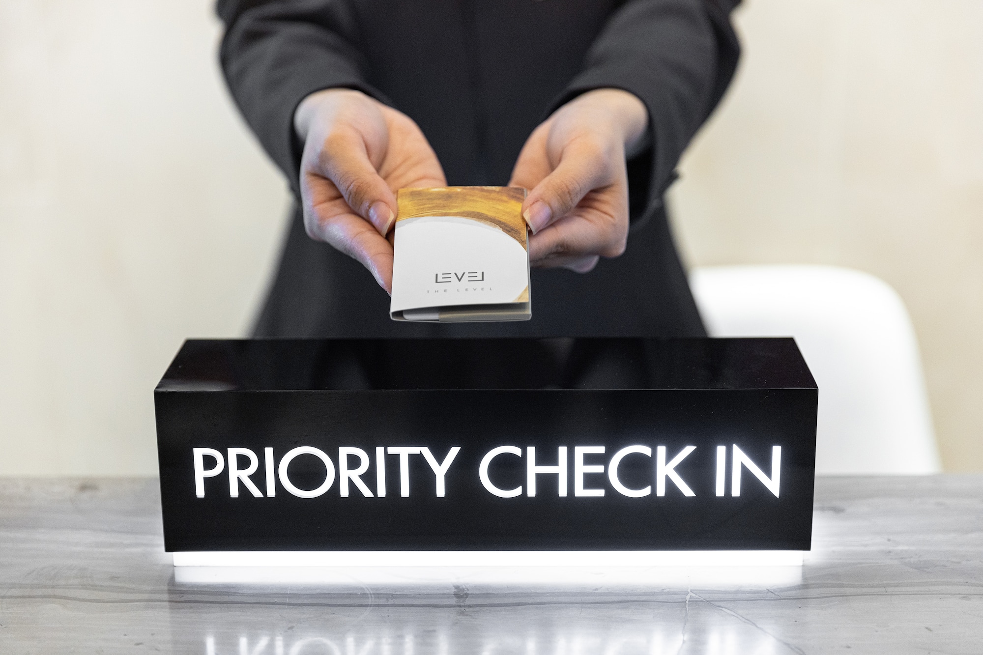 Hands giving "The Level" key card at a hotel Priority Check-In desk.
