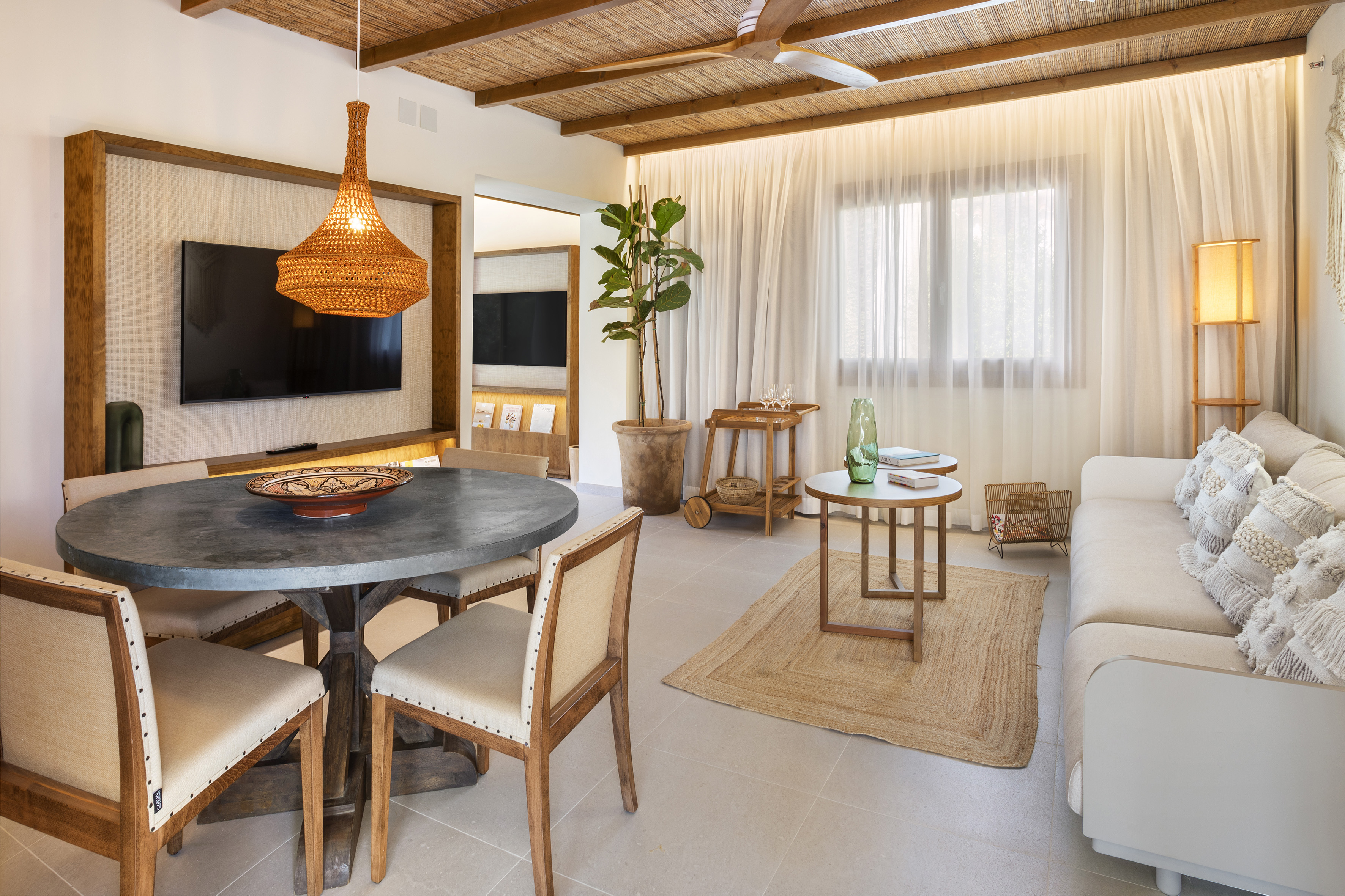 Rustic modern living dining area with rattan ceiling, sofa, and wood accents.