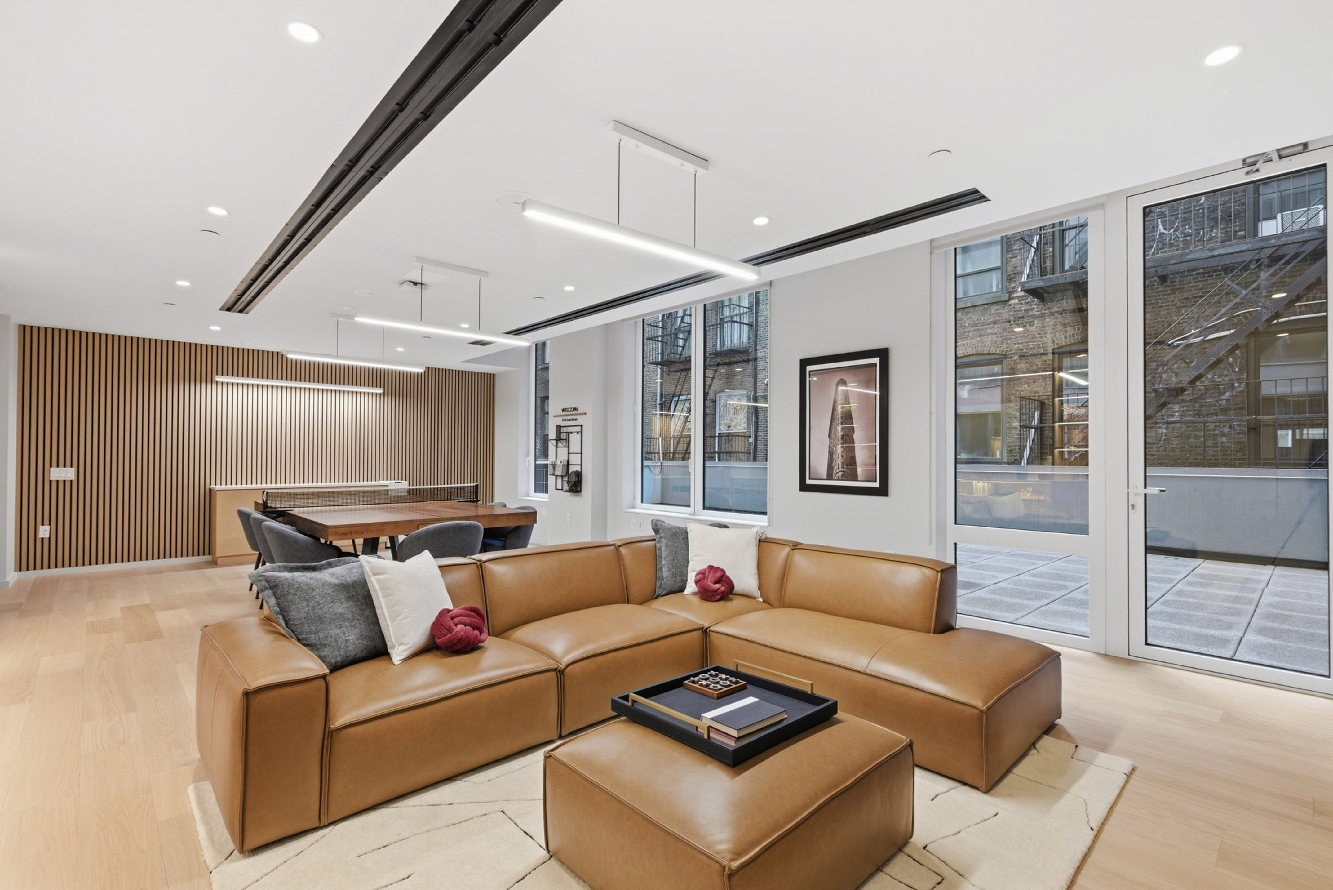 Brown leather sectional lounge with wood slat wall and bright windows.