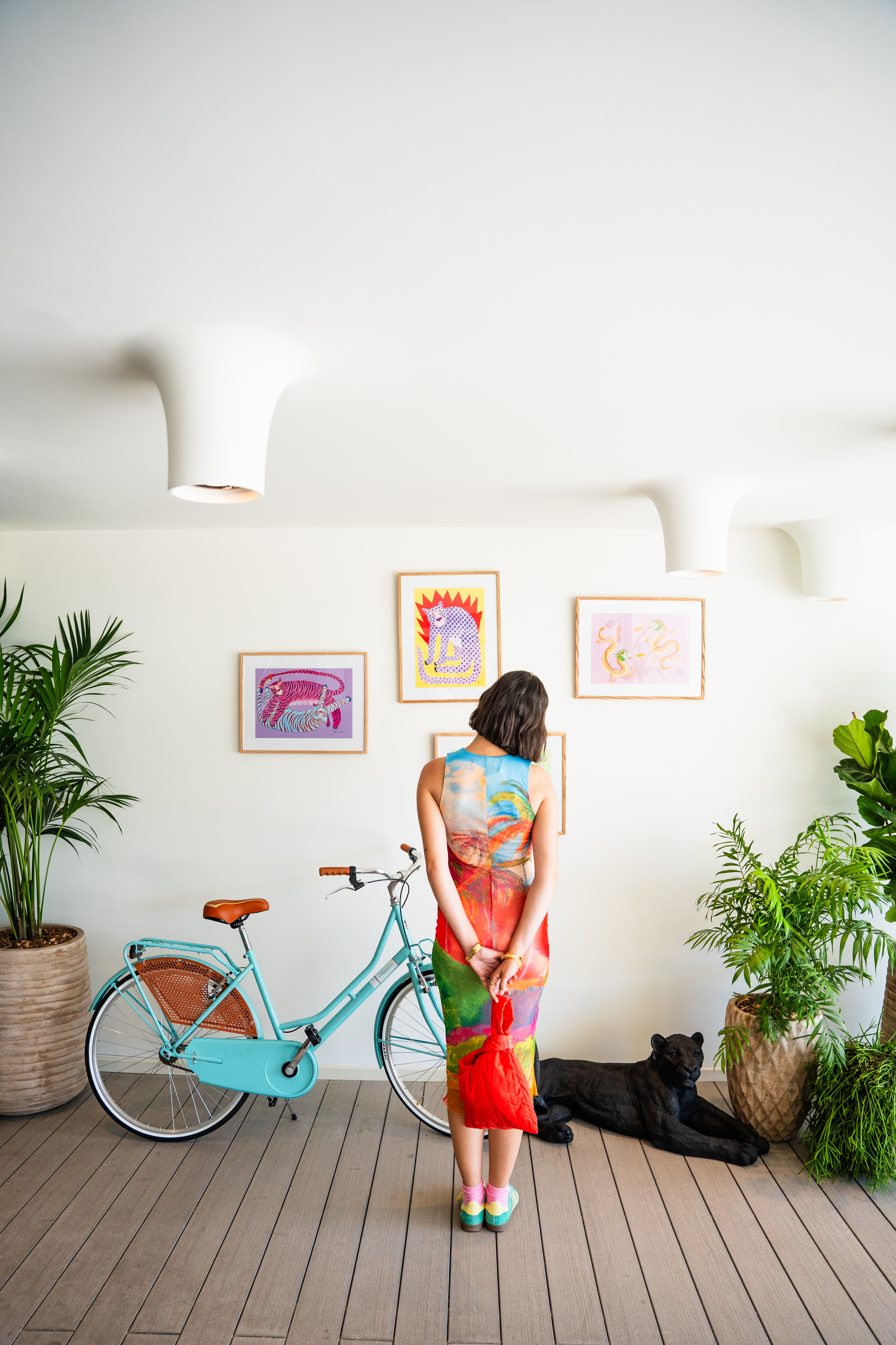 Woman in colorful dress, turquoise bicycle, vibrant art, modern interior.