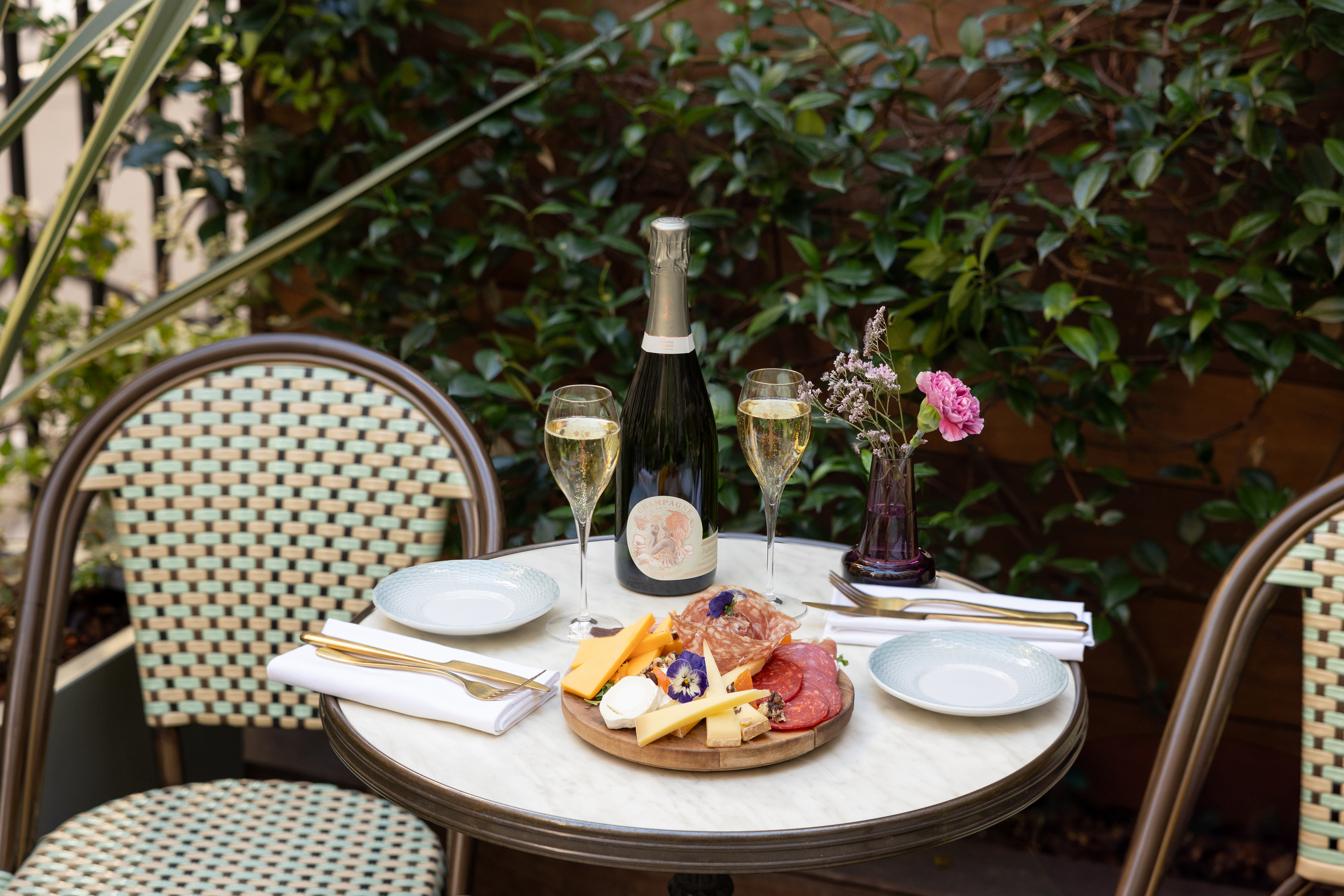 Champagne and charcuterie board on an outdoor marble bistro table.