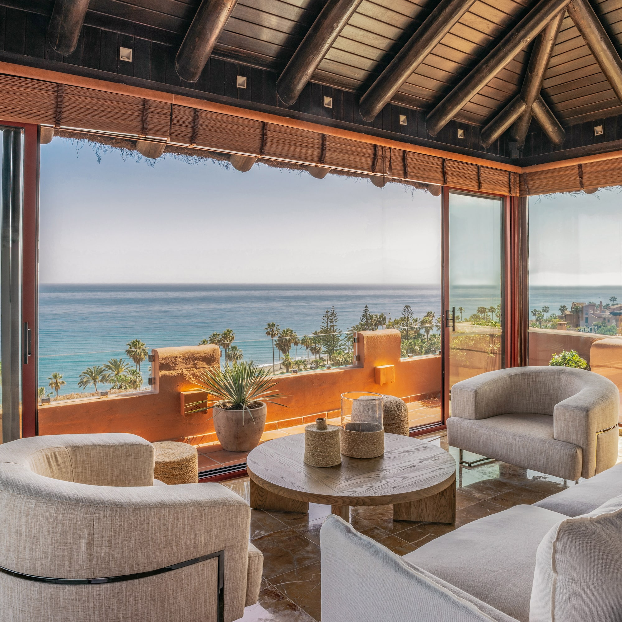 Luxury living room with ocean view, modern furniture, and wooden beamed ceiling.