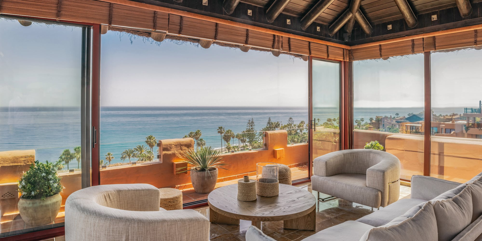 Luxury living room with ocean view, modern furniture, and wooden beamed ceiling.