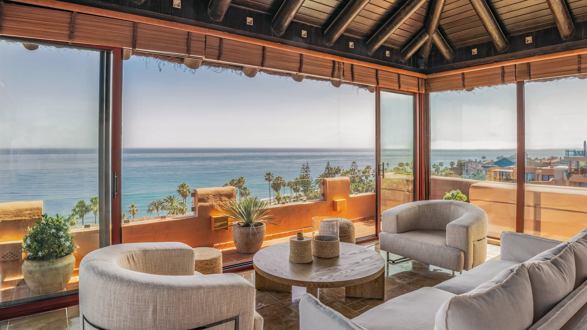 Luxury living room with ocean view, modern furniture, and wooden beamed ceiling.