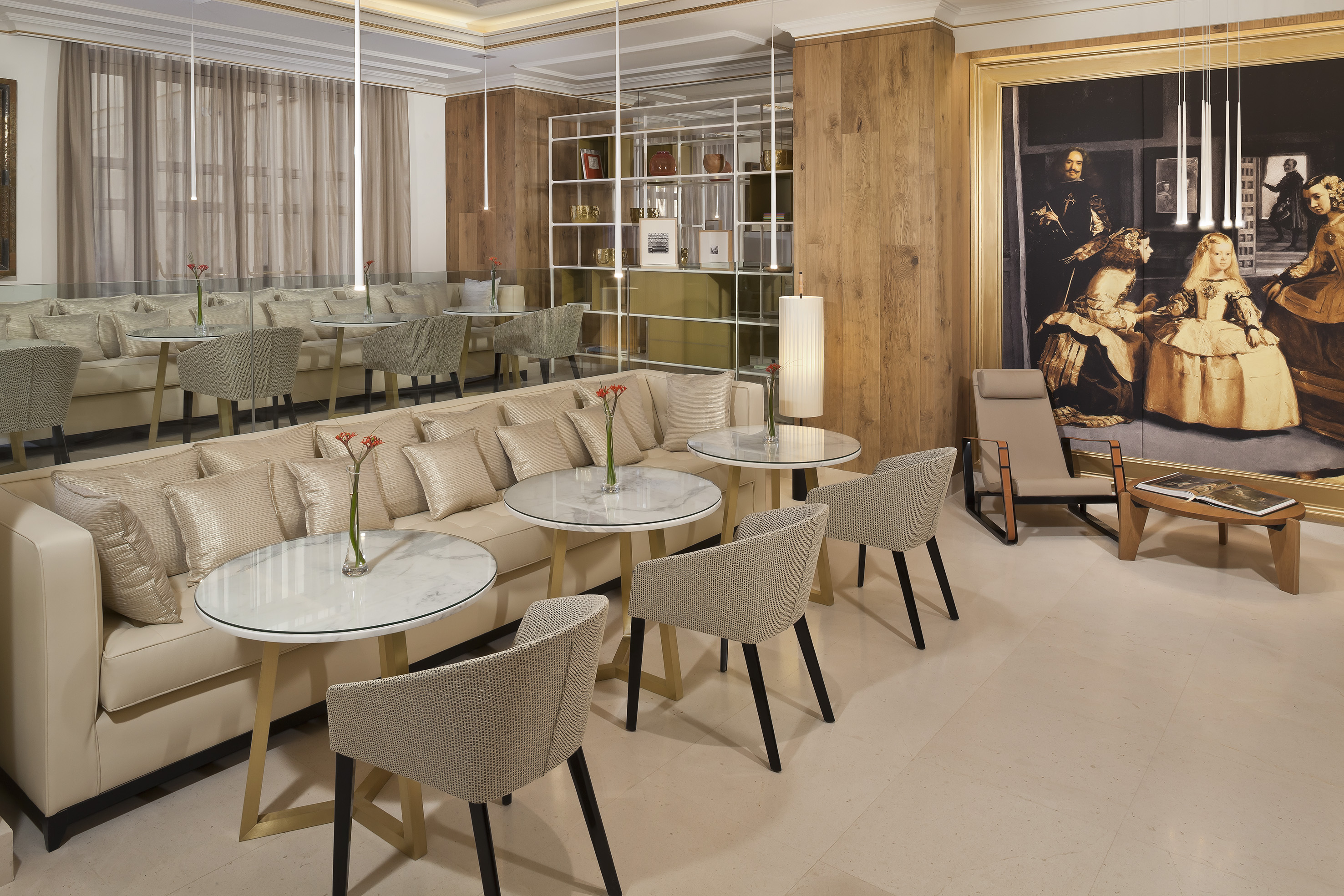Modern luxury lounge with beige sofa, marble tables, and large framed artwork.