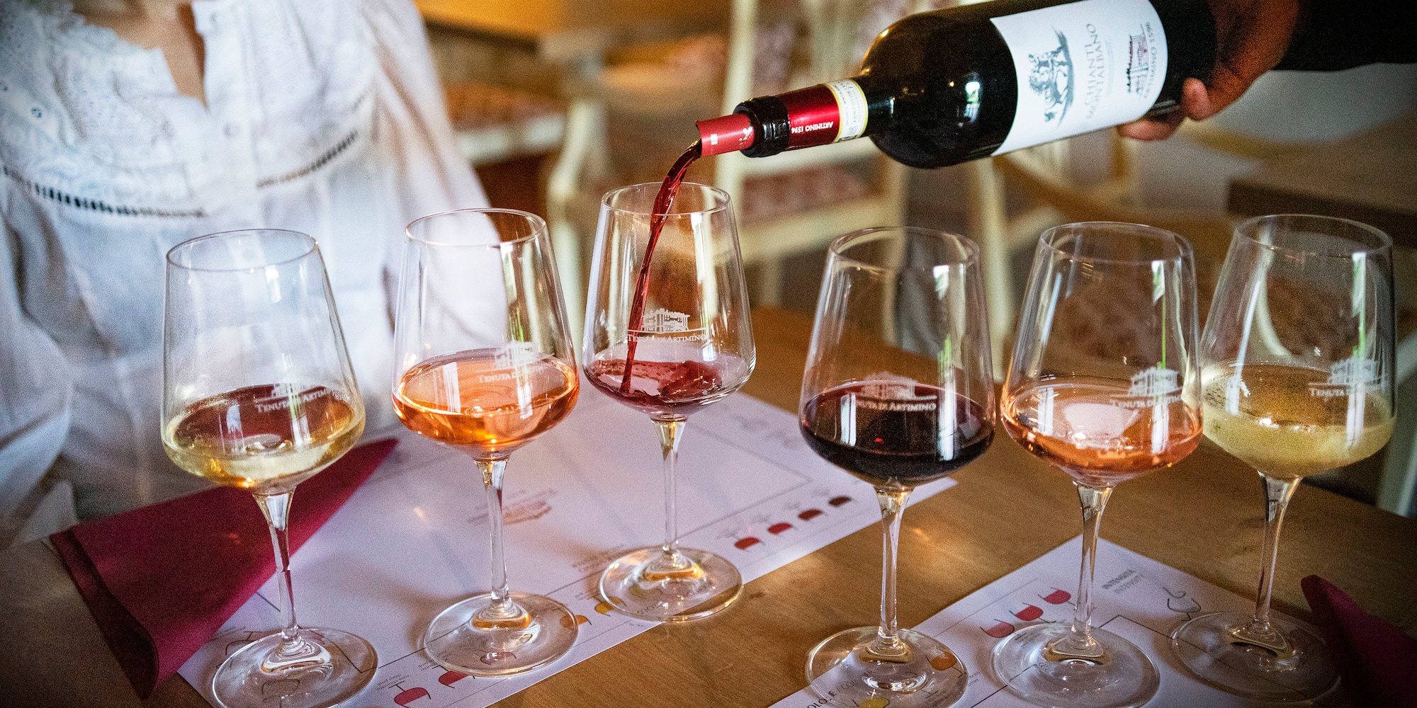 Hand pouring Tenuta Artimino Chianti red wine at a multi-varietal tasting.