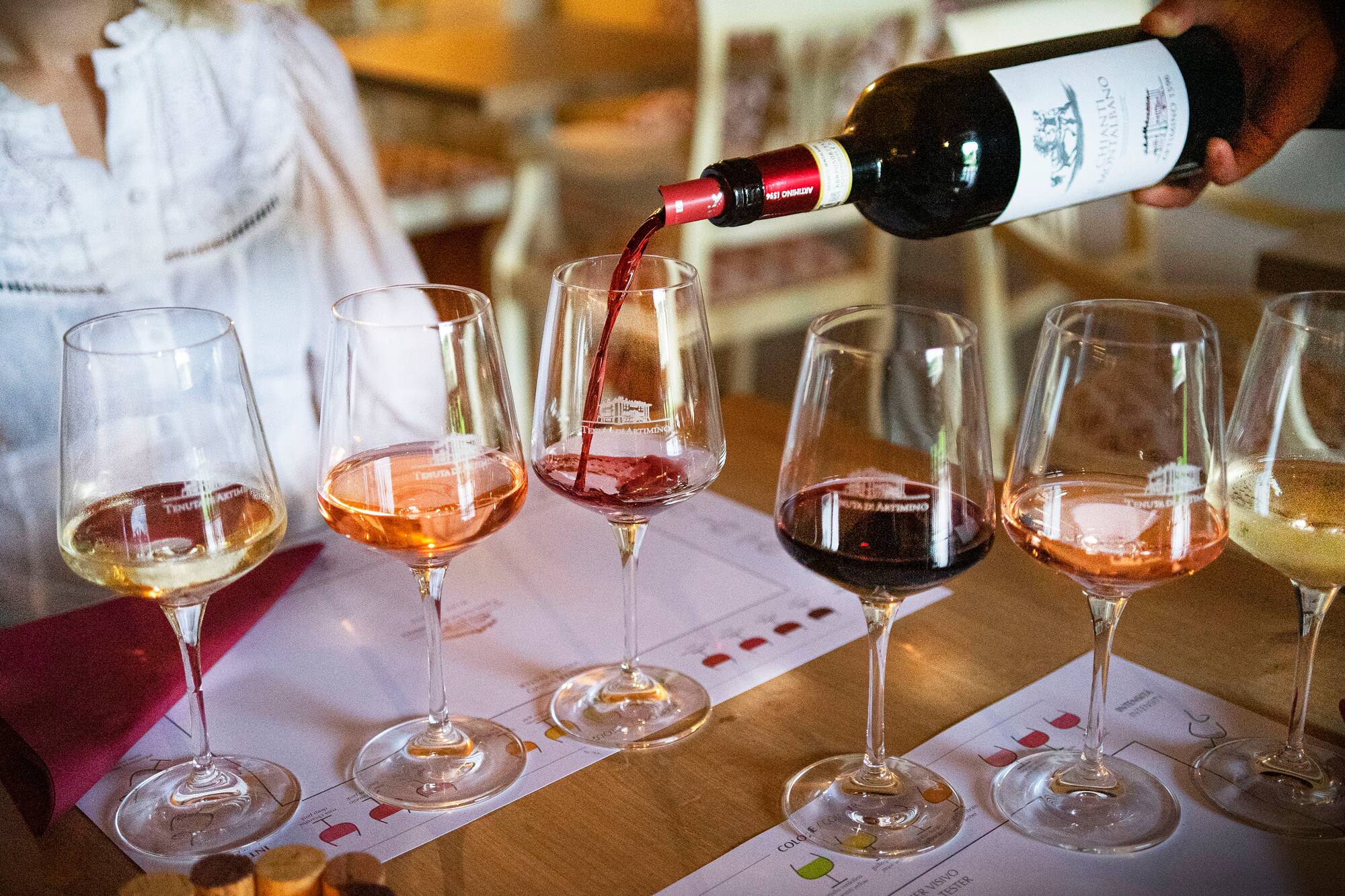 Hand pouring Tenuta Artimino Chianti red wine at a multi-varietal tasting.