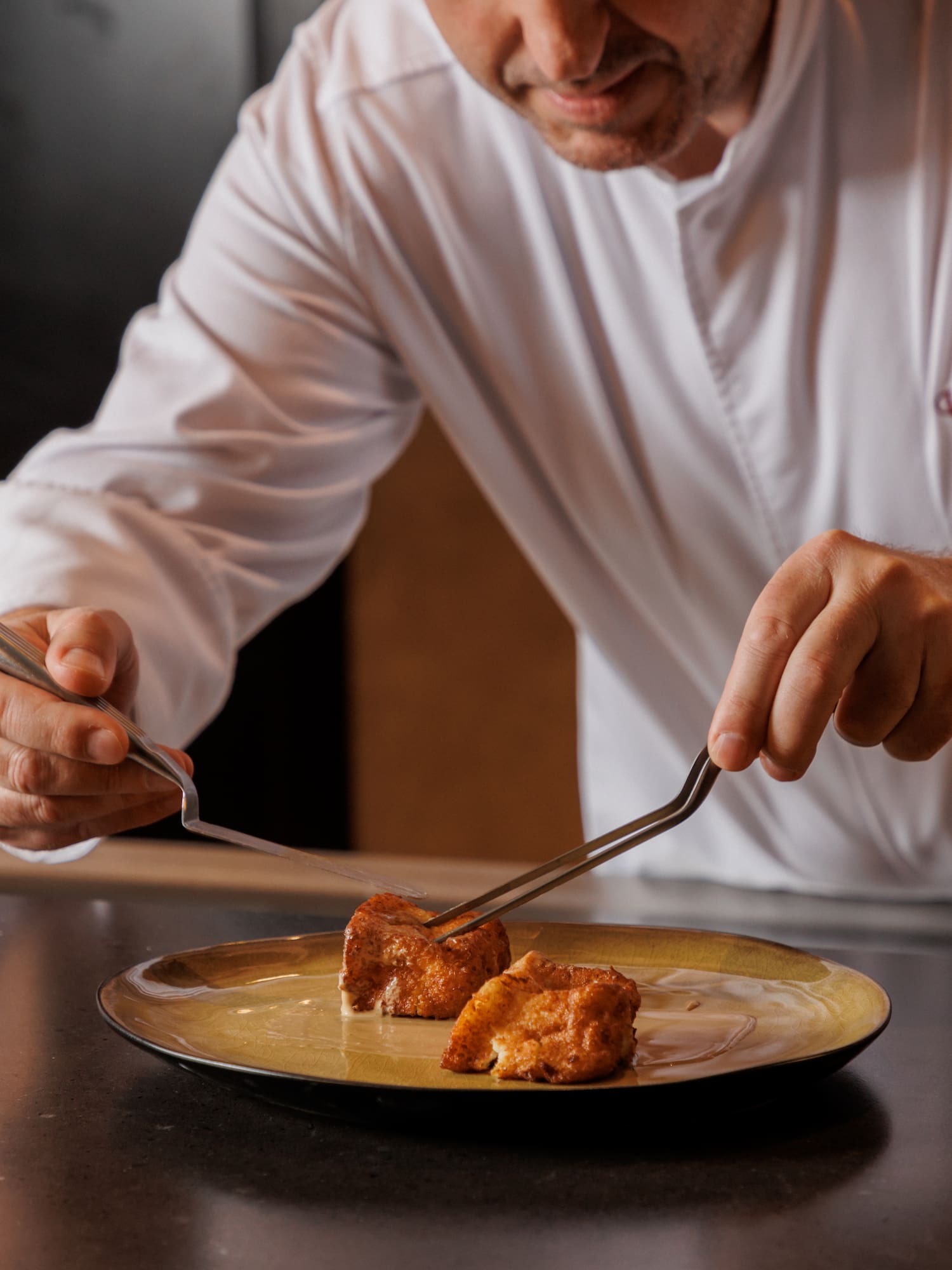 a man holding tongs to a piece of food