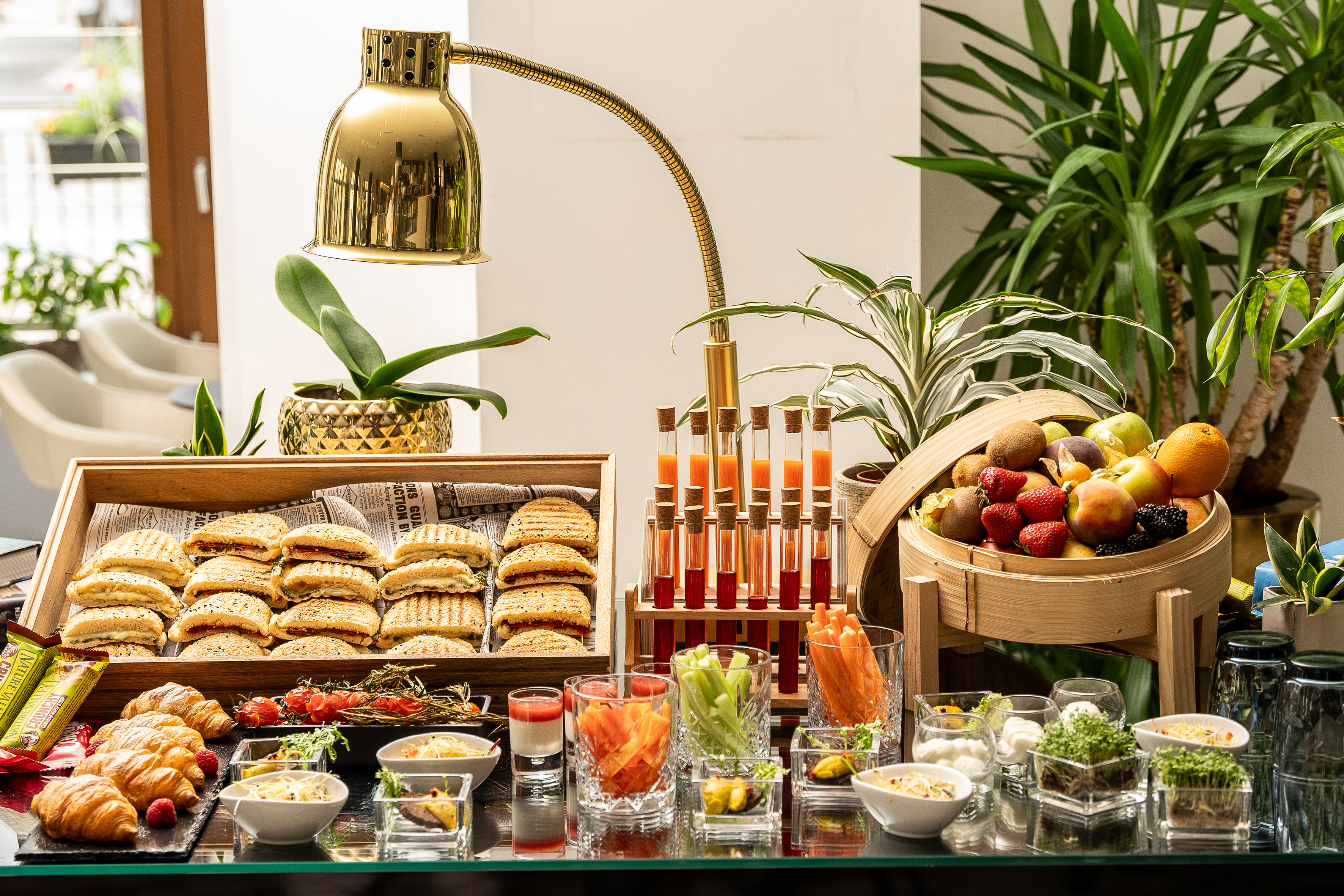 Breakfast buffet with fresh fruit, pastries, grilled sandwiches, and healthy juice shots.