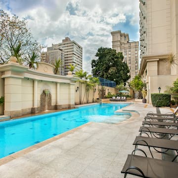 a pool with chairs and a fountain in the background