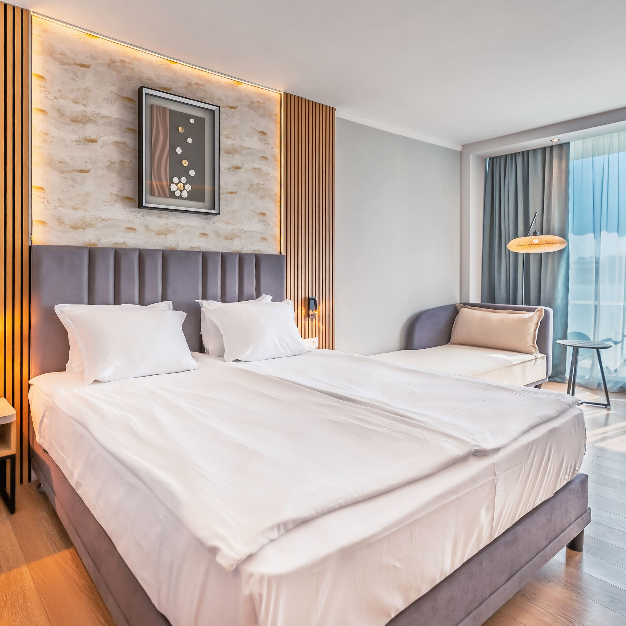 Modern hotel room with large bed, wood paneling, and balcony access.