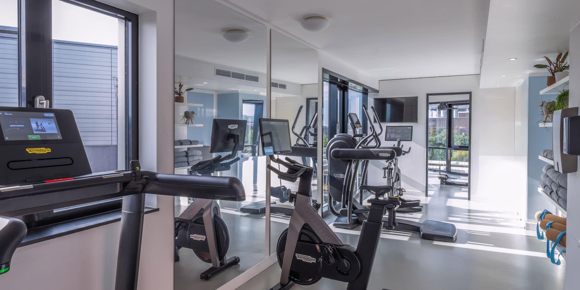 Modern gym with Technogym treadmill, bikes, ellipticals, and mirrors. - Khu vực tập thể dục - INNSiDE Wolfsburg, Wolfsburg