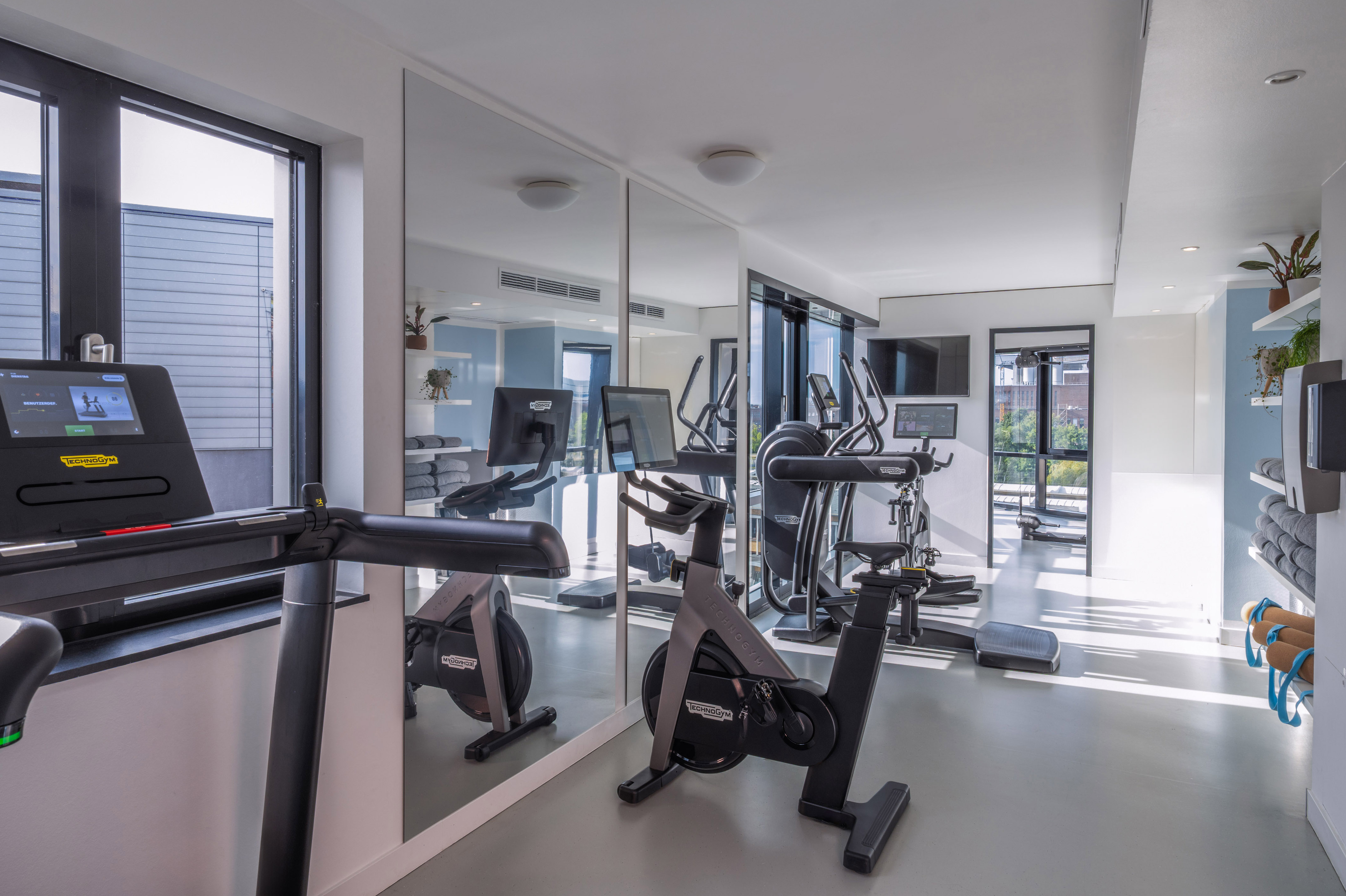 Modern gym with Technogym treadmill, bikes, ellipticals, and mirrors. - Khu vực tập thể dục - INNSiDE Wolfsburg, Wolfsburg