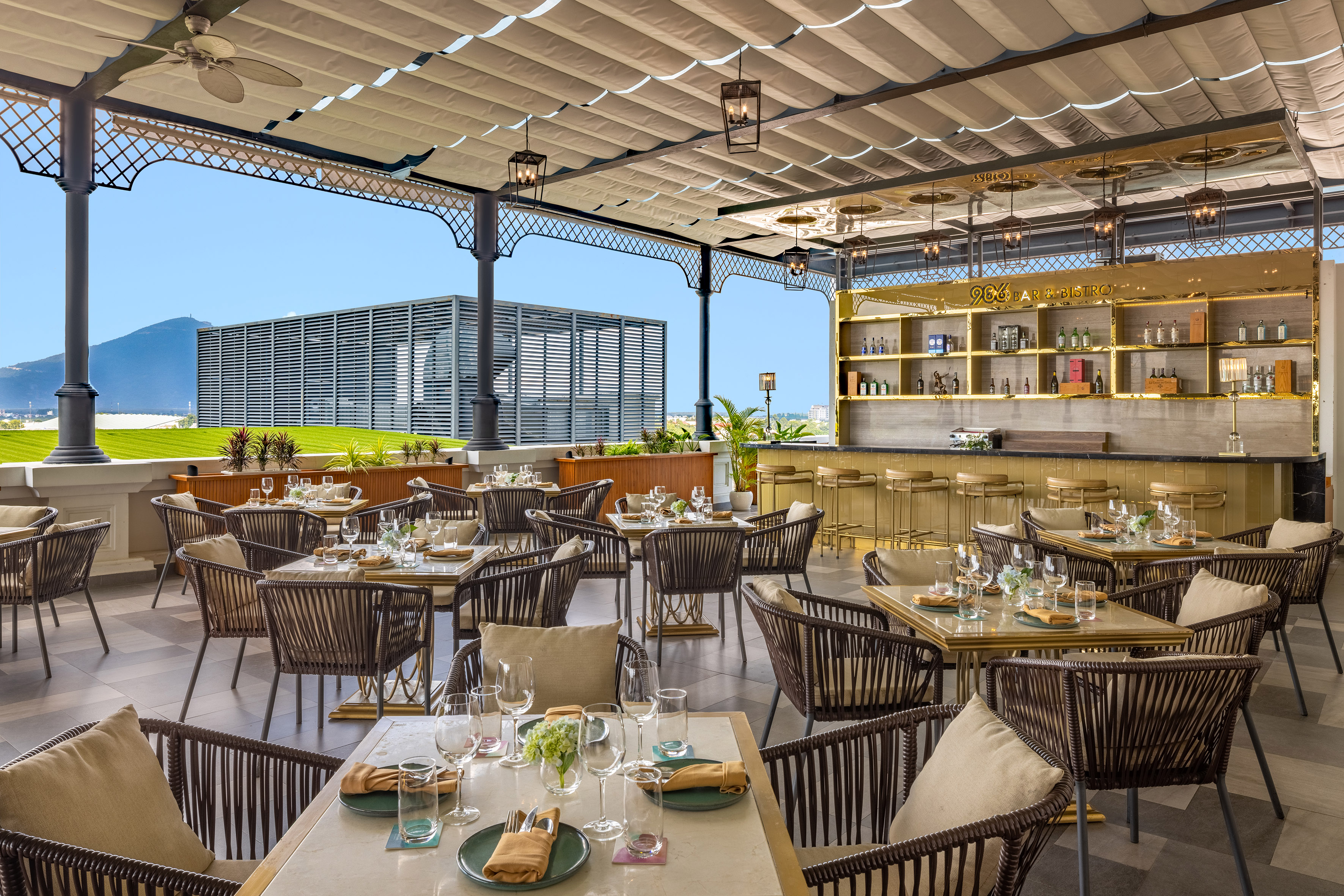 Stylish outdoor Bar & Bistro terrace with set dining tables and golden bar.