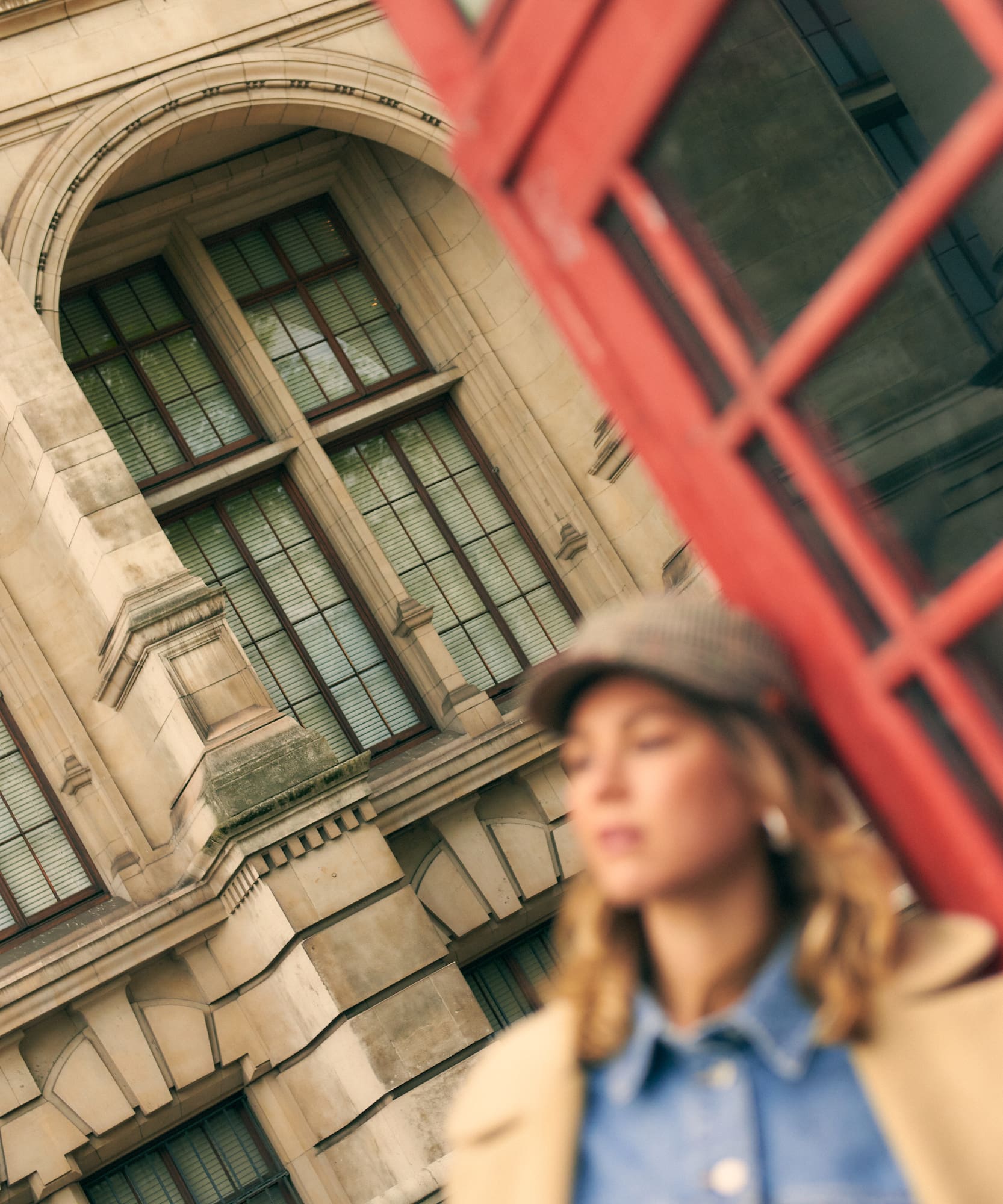 Cabina telefónica roja, edificio londinense, mujer con gorra.