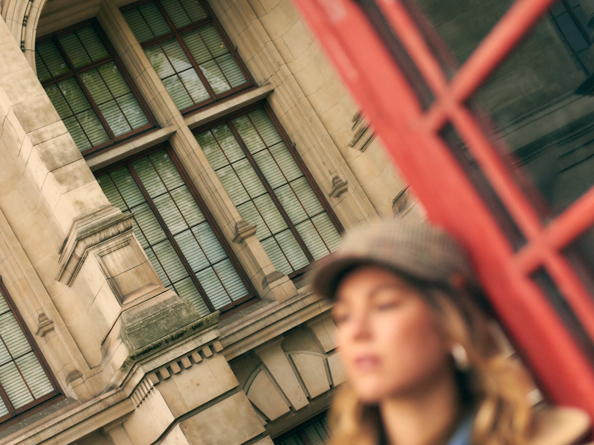 a woman leaning against a red telephone booth