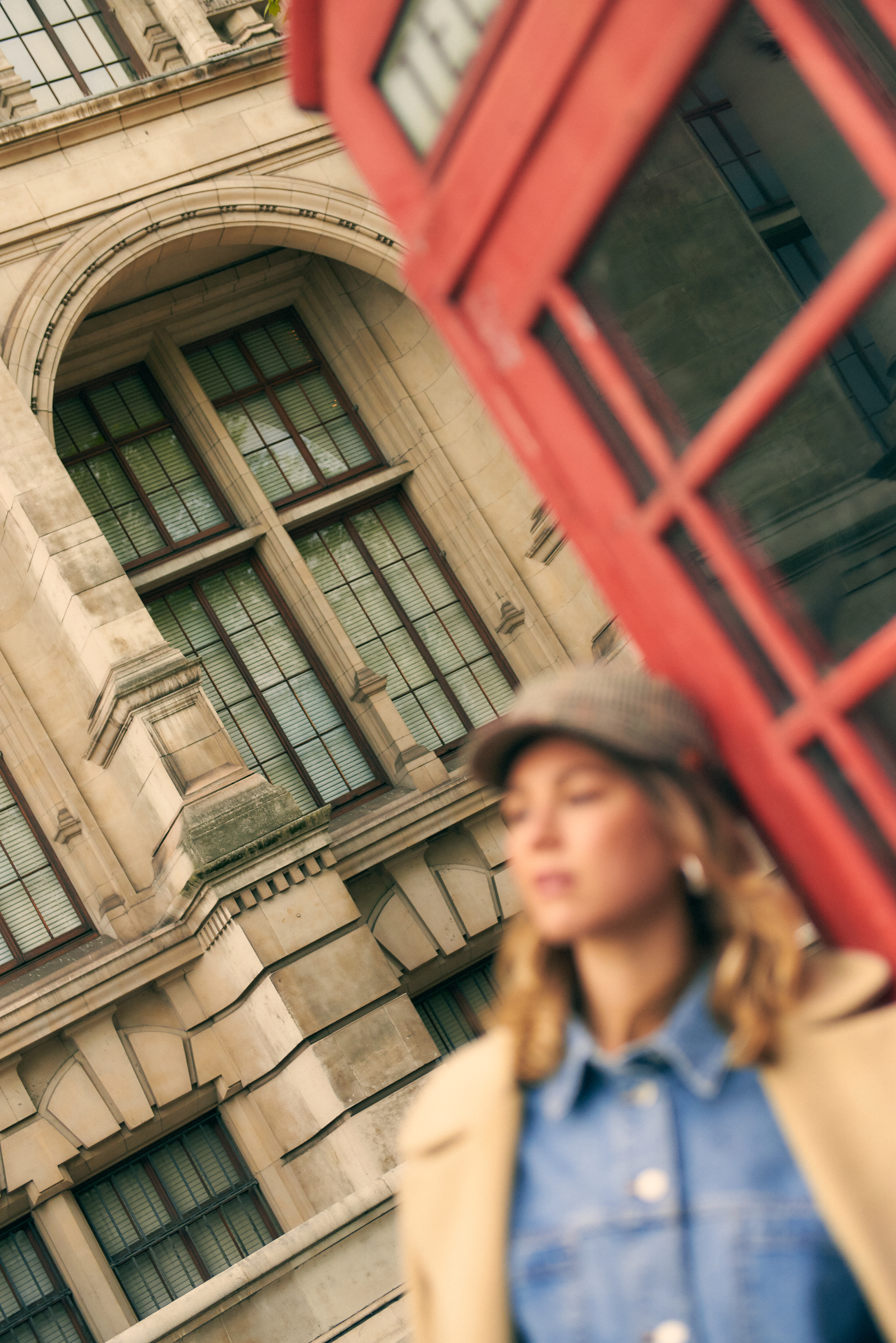 Cabina telefónica roja, edificio londinense, mujer con gorra.