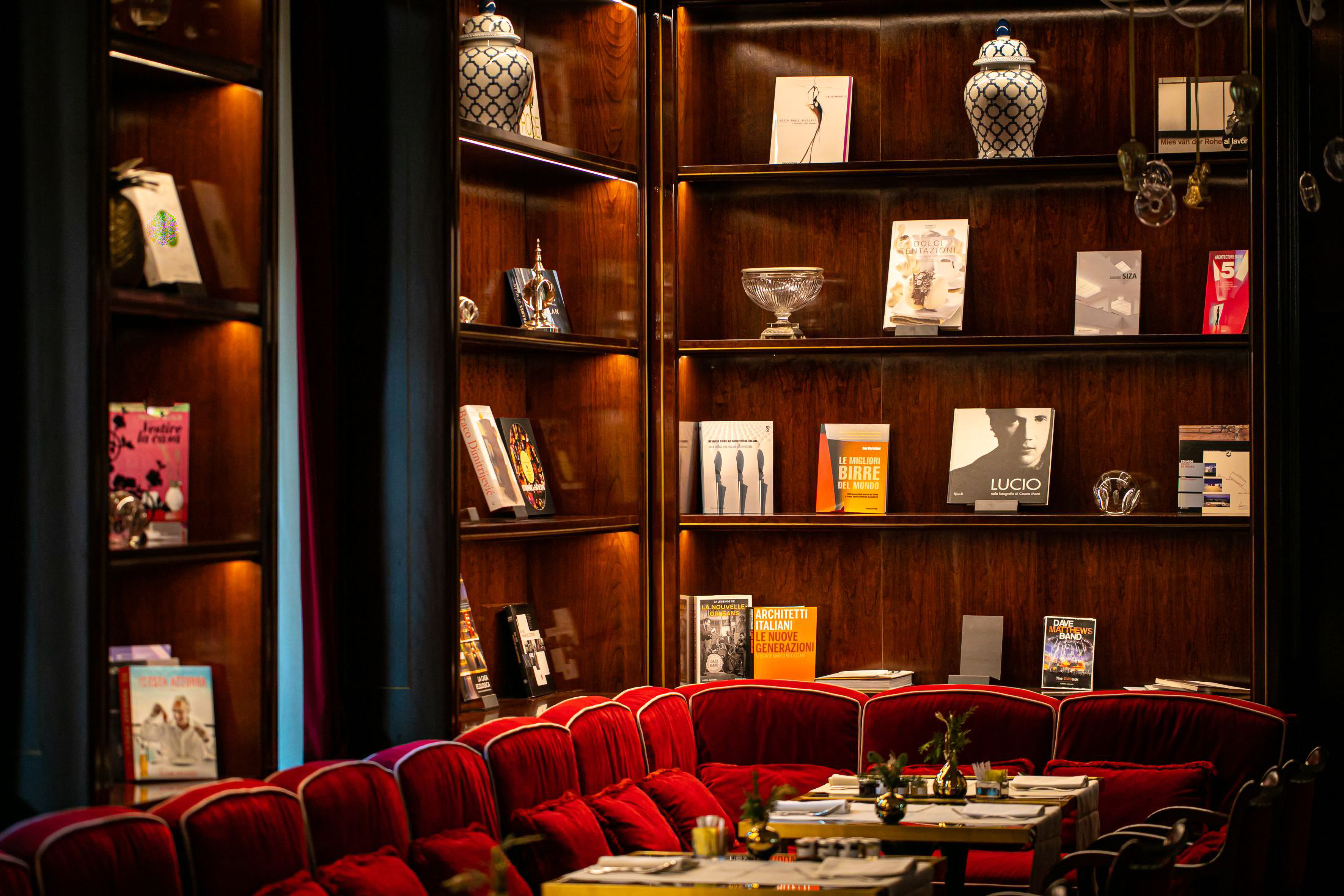 a room with red chairs and tables and books on shelves