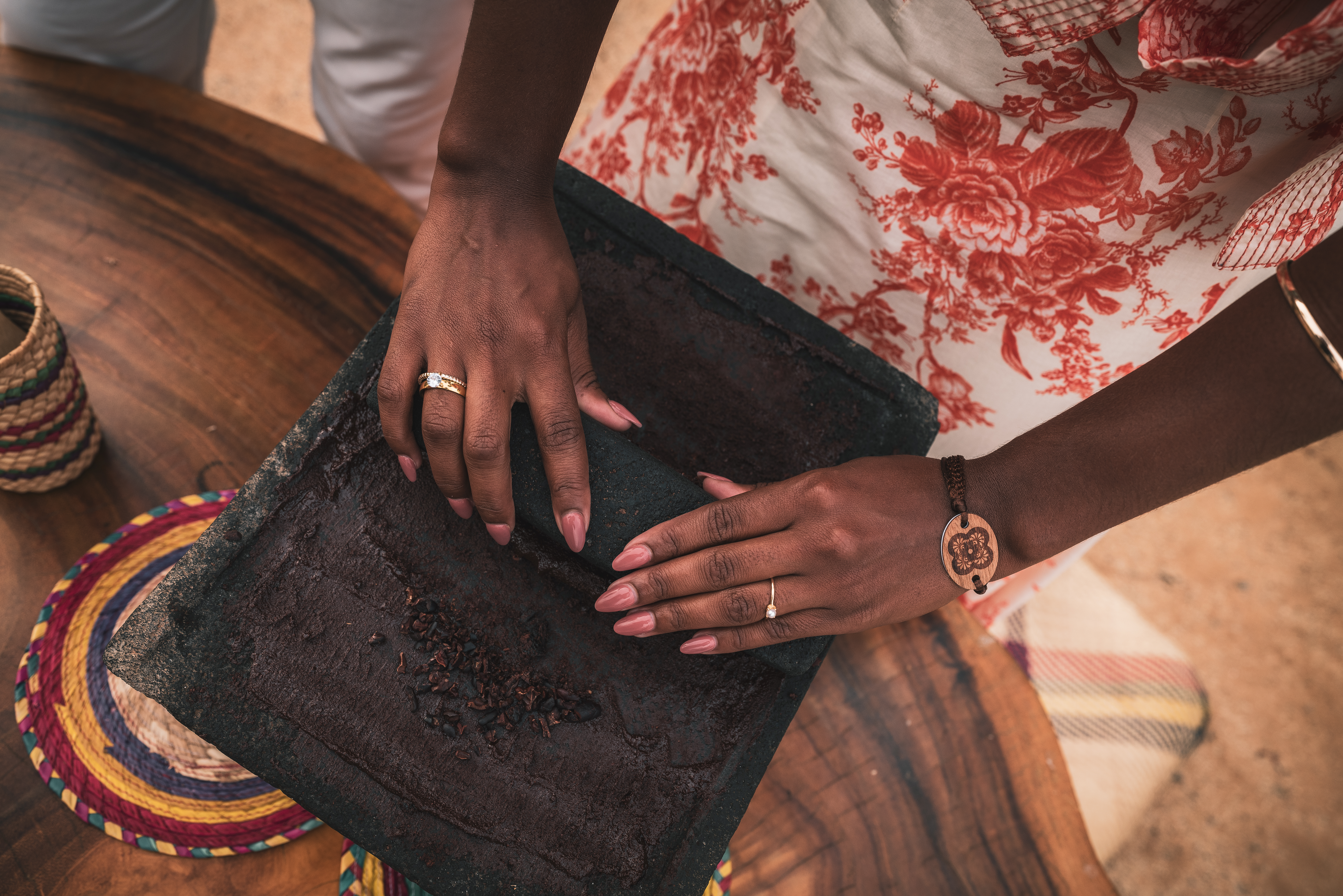 Hands grinding cacao beans on a traditional stone metate for chocolate.