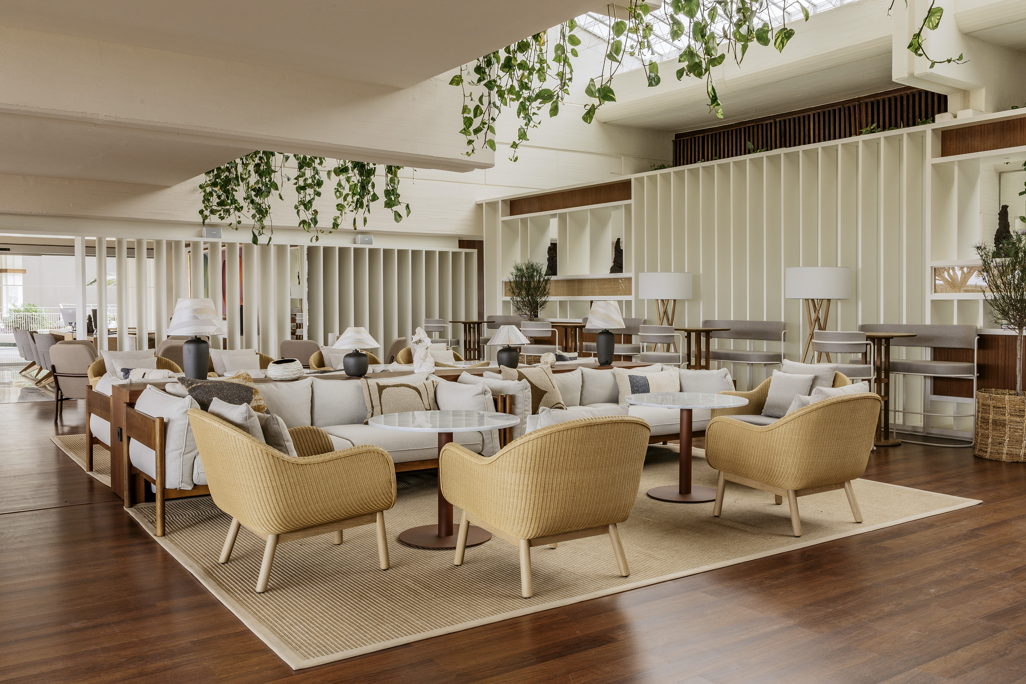 Modern hotel lounge with comfortable seating, hanging plants, and natural light.