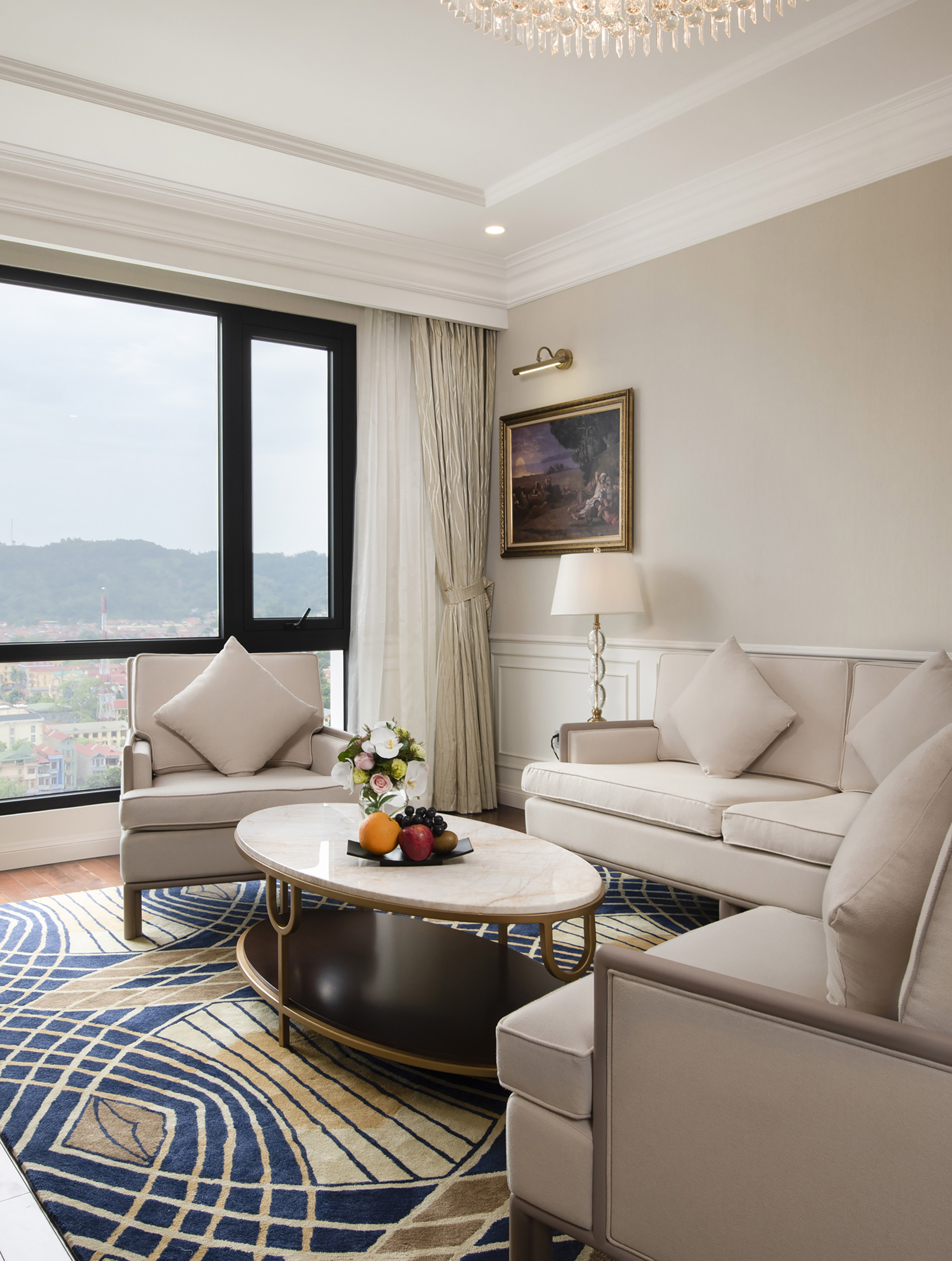 Elegant living room with beige sofa, marble coffee table, city view, patterned rug.