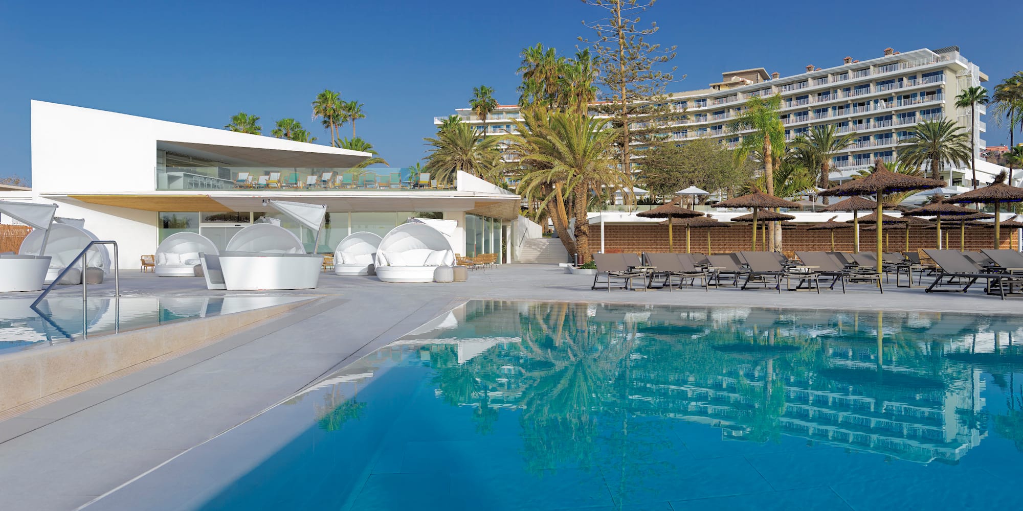 a swimming pool with lounge chairs and a building in the background