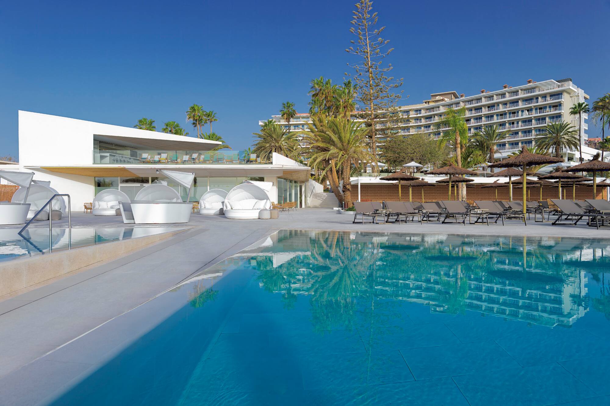 a swimming pool with lounge chairs and a building in the background