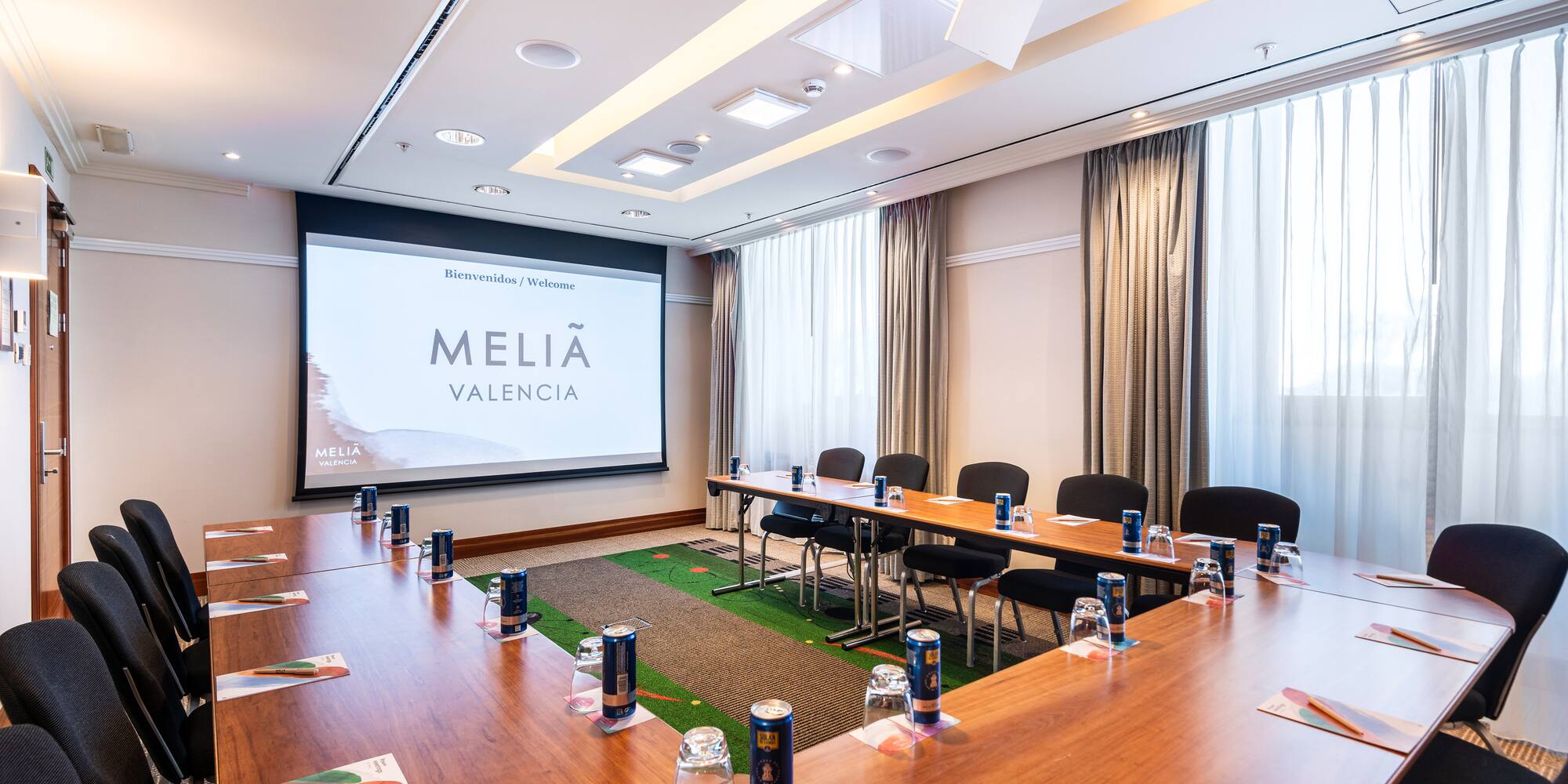 a room with a large screen and tables and chairs