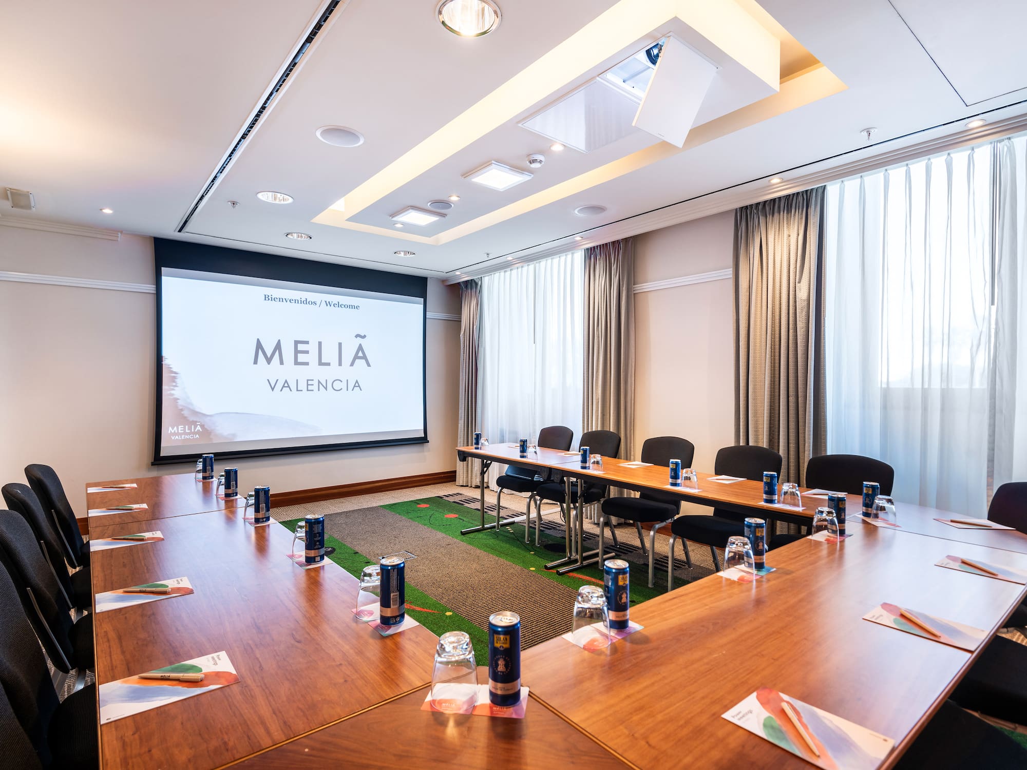 a room with a large screen and tables and chairs