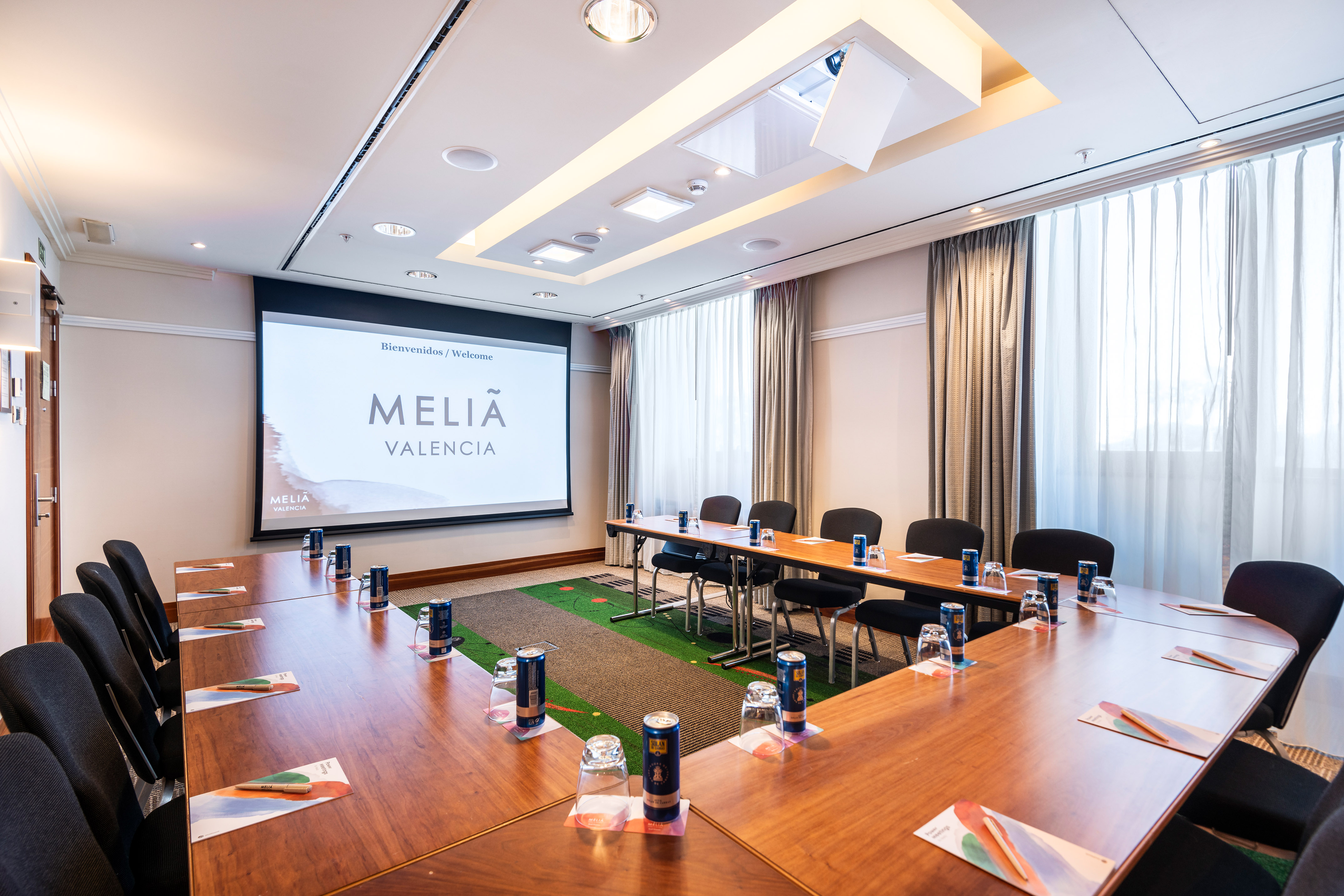 a room with a large screen and tables and chairs