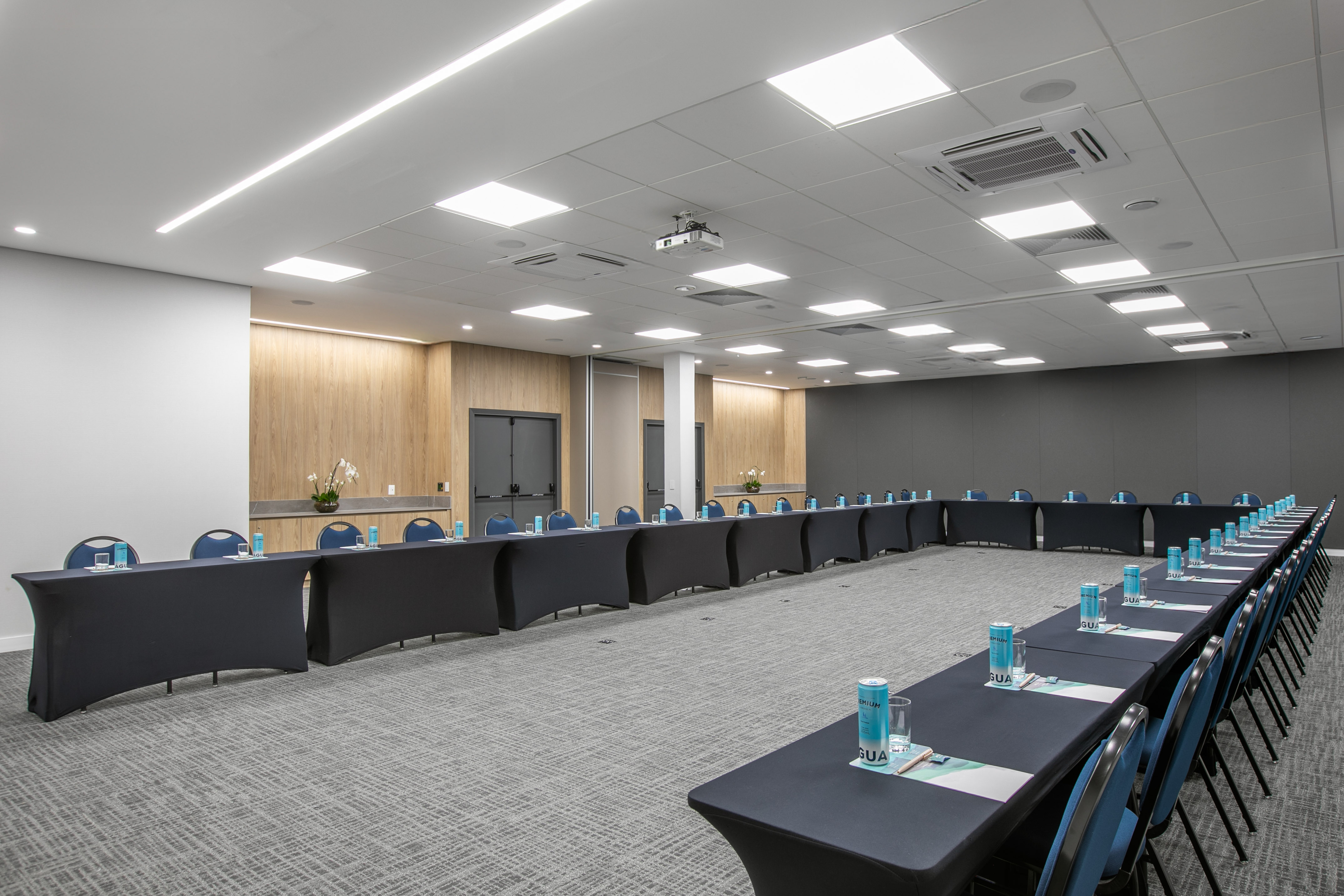U-shaped conference room with black tables, blue chairs, and modern lighting.