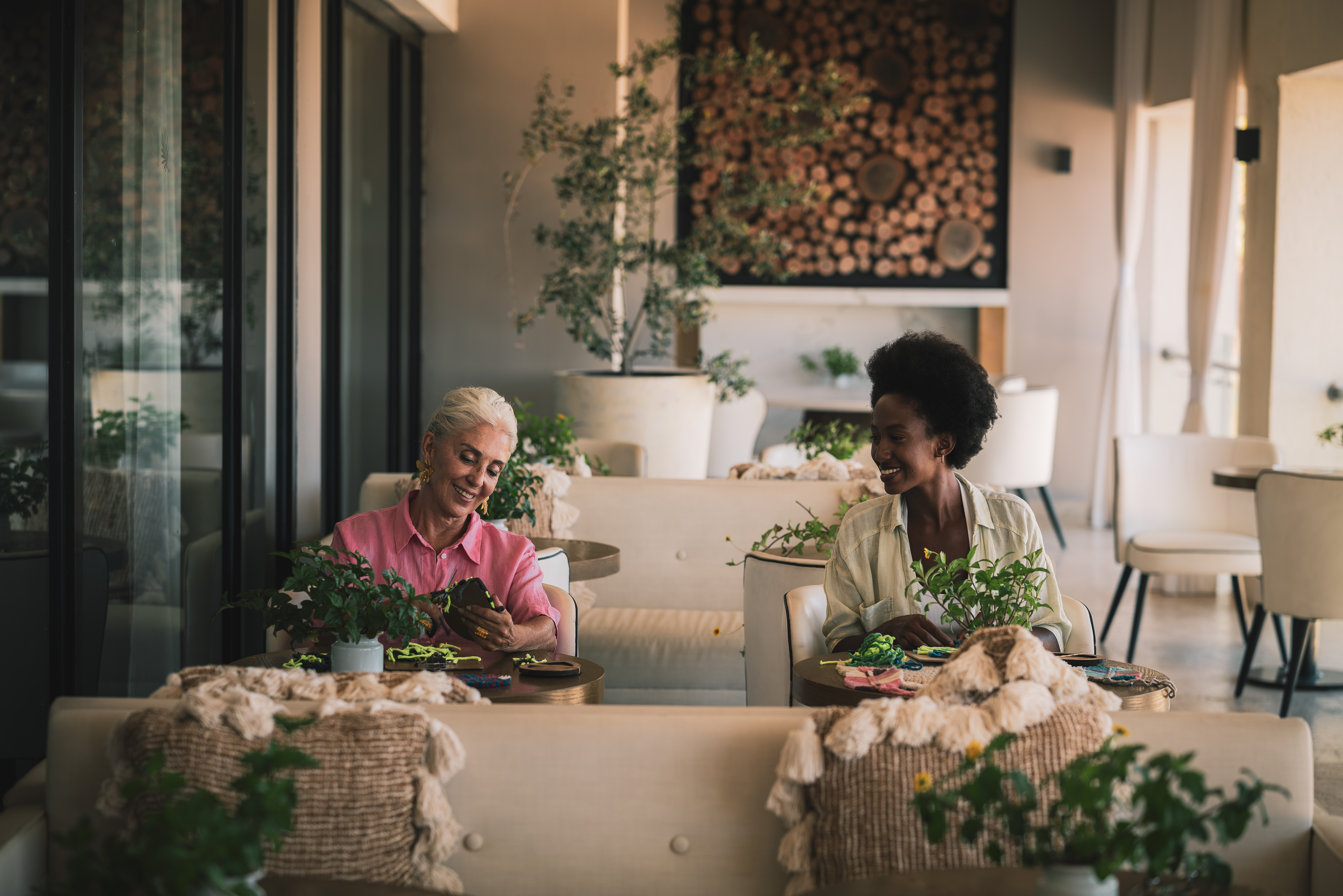 Diverse women smiling, crafting in a bright, modern lounge setting.