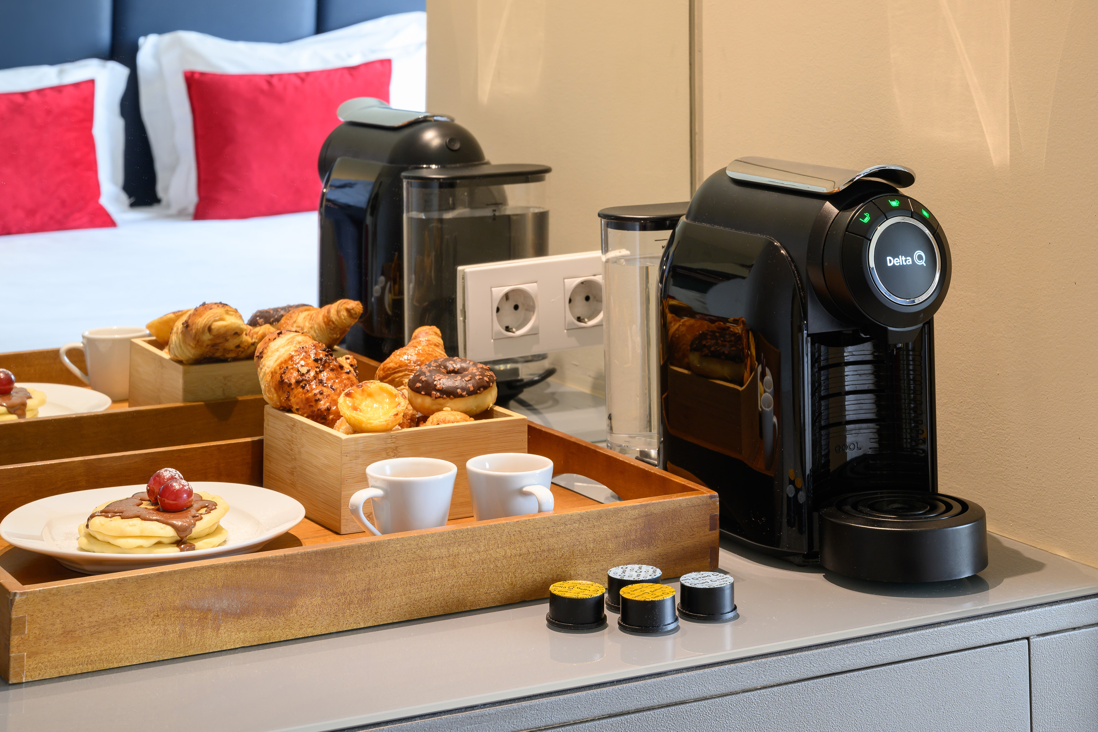 Delta Q coffee machine and hotel breakfast tray with pastries, pancakes, coffee.