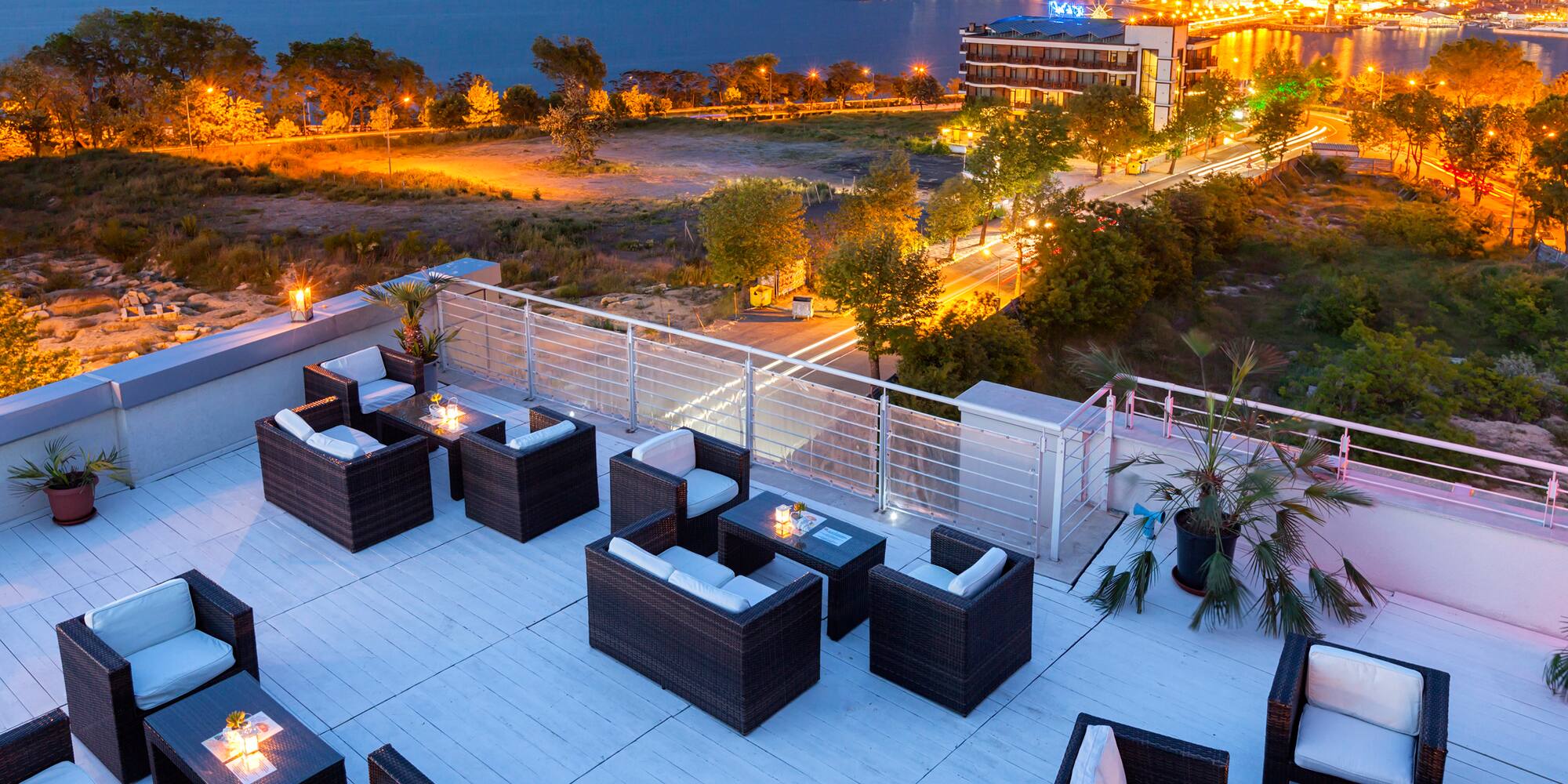 a rooftop patio with chairs and a city in the background
