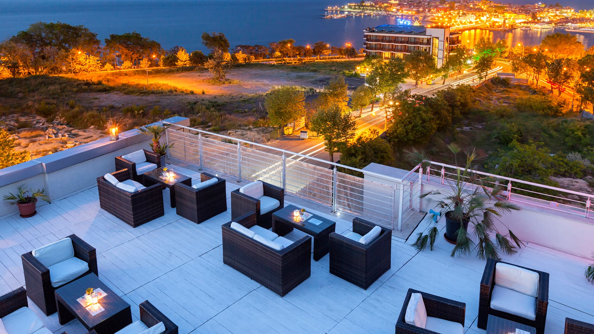 a rooftop patio with chairs and a city in the background